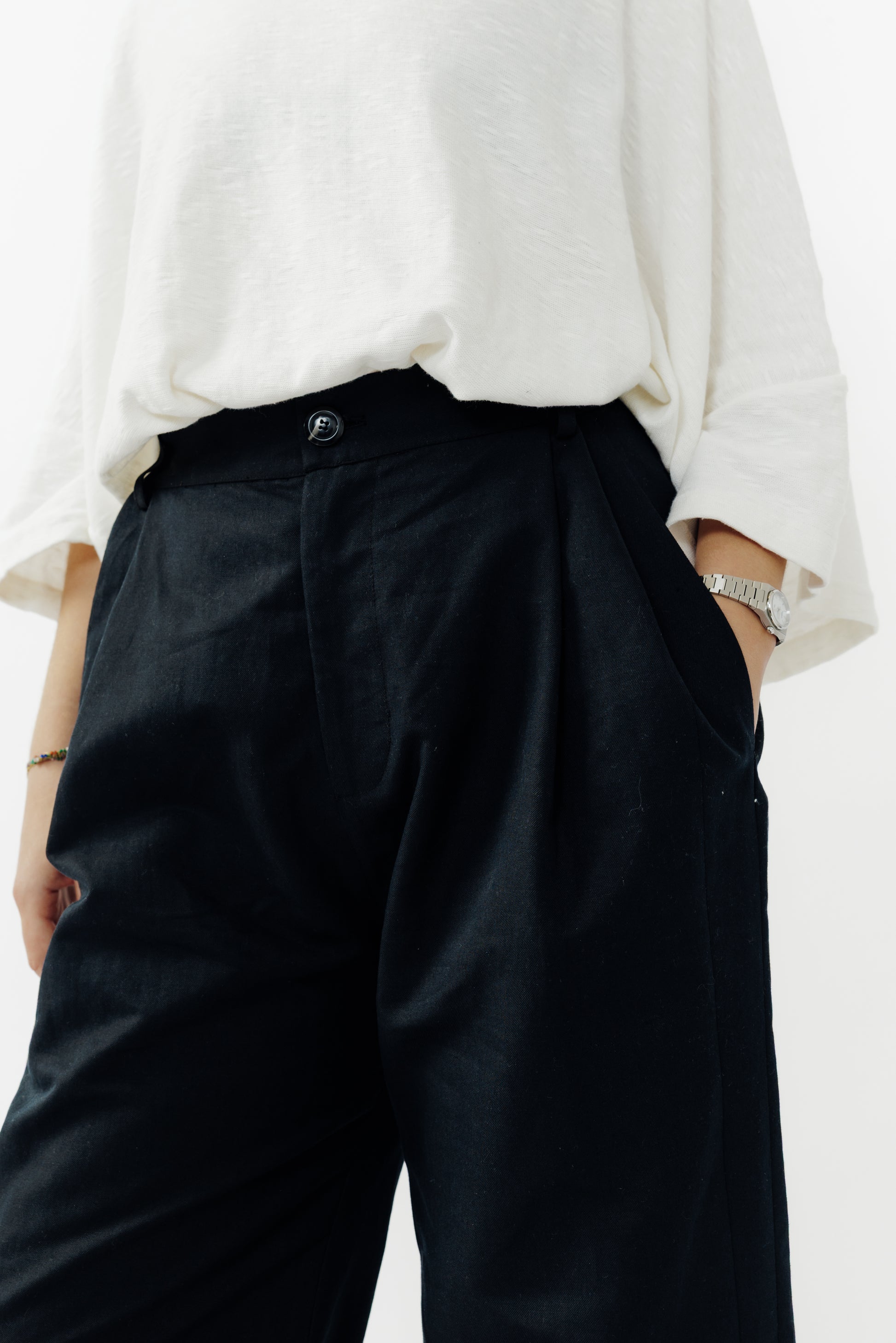 Pantalon droit de la marque Aïdama, coupe ample en coton et lin noir avec sangles ajustables à la taille. Porté par une mannequin femme et vu de face zoomé sur la ceinture.