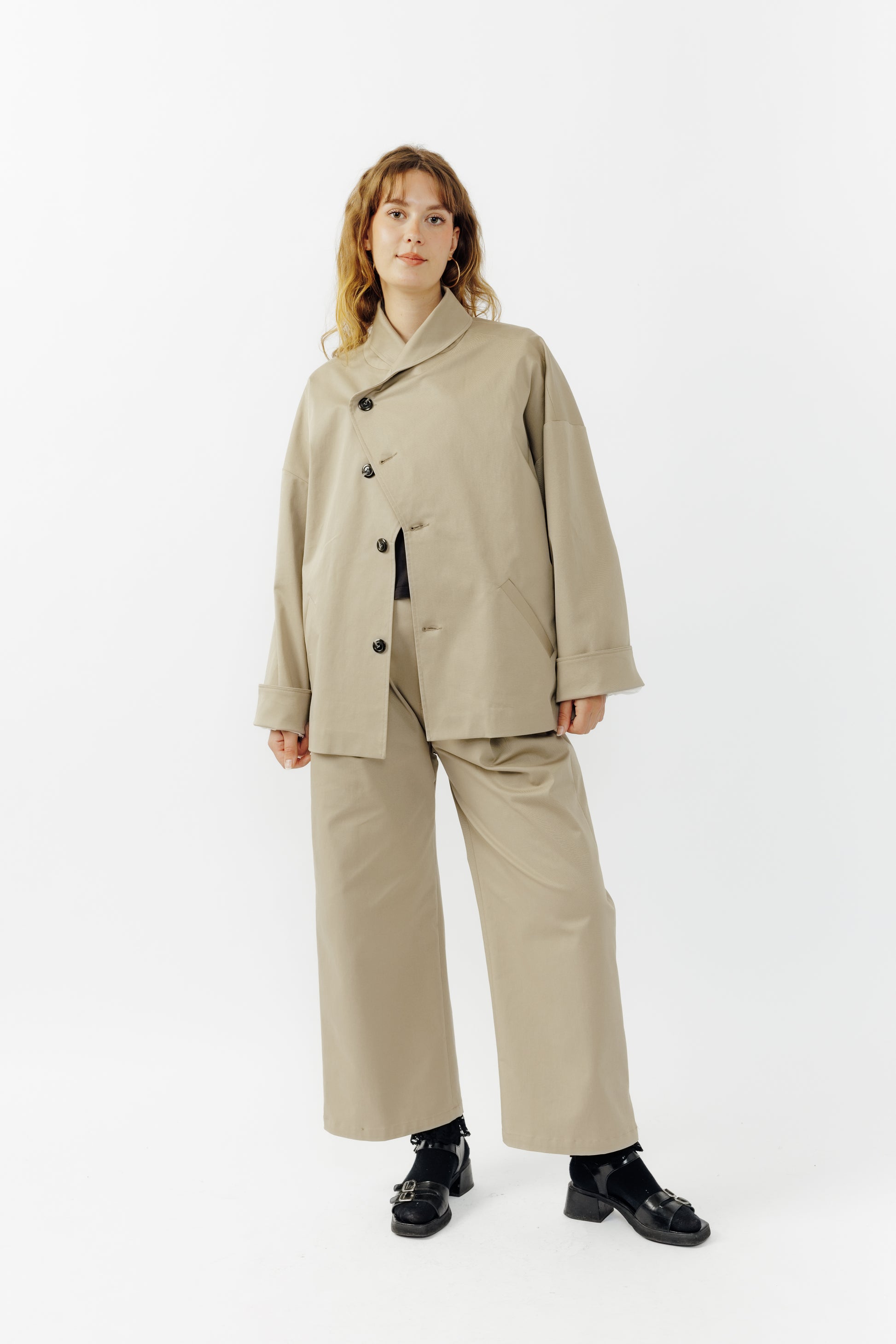 Pantalon droit de la marque Aïdama, coupe ample en gabardine de coton beige avec sangles ajustables à la taille. Porté par une mannequin femme et vu de face.