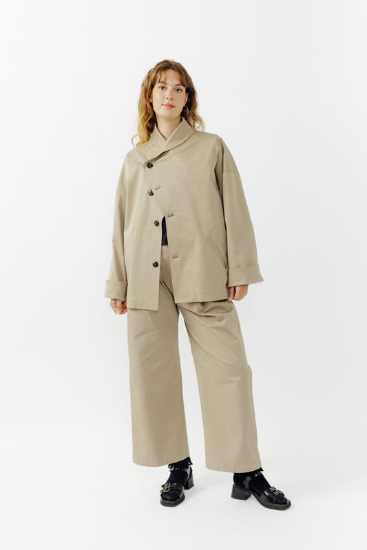Pantalon droit de la marque Aïdama, coupe ample en gabardine de coton beige avec sangles ajustables à la taille. Porté par une mannequin femme et vu de face.