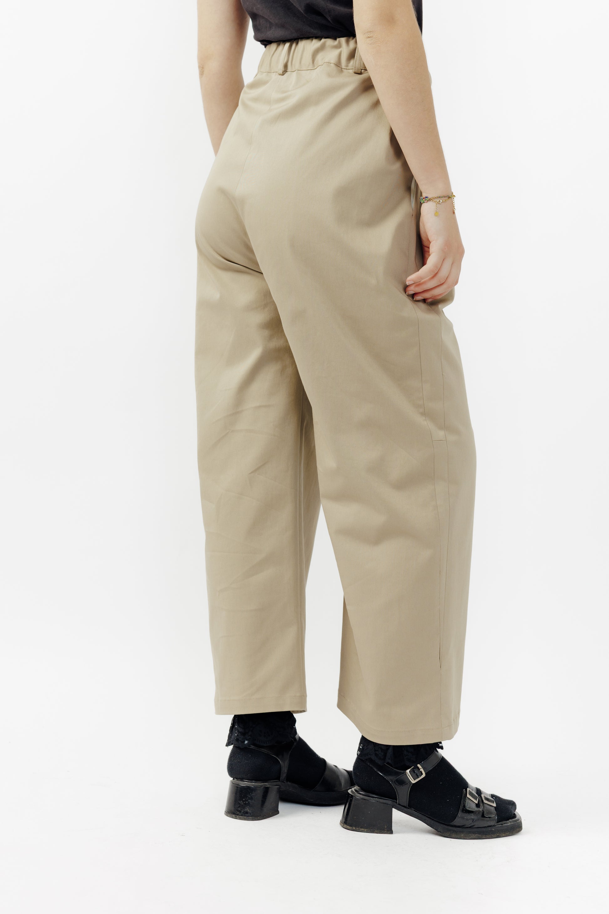 Pantalon droit de la marque Aïdama, coupe ample en gabardine de coton beige avec sangles ajustables à la taille. Porté par une mannequin femme et vu de dos.