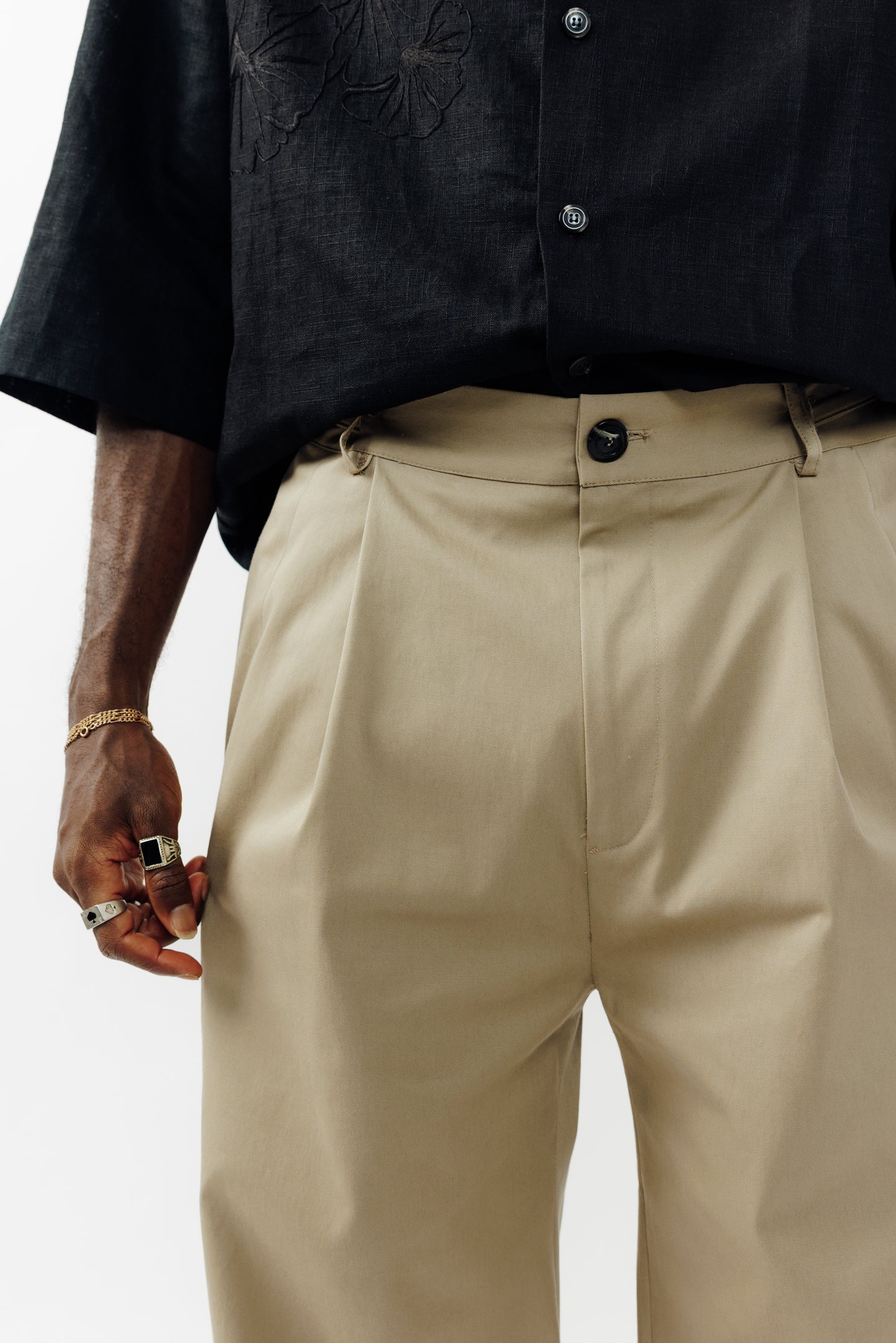 Pantalon droit de la marque Aïdama, coupe ample en gabardine de coton beige avec sangles ajustables à la taille. Porté par un mannequin homme et vu de face zoomé sur la ceinture.