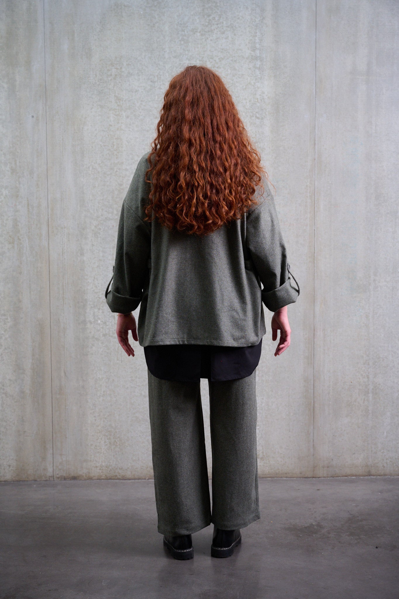 Pantalon droit de la marque Aïdama, coupe large en flanelle de laine grise. Porté par une mannequin femme et vue de dos.