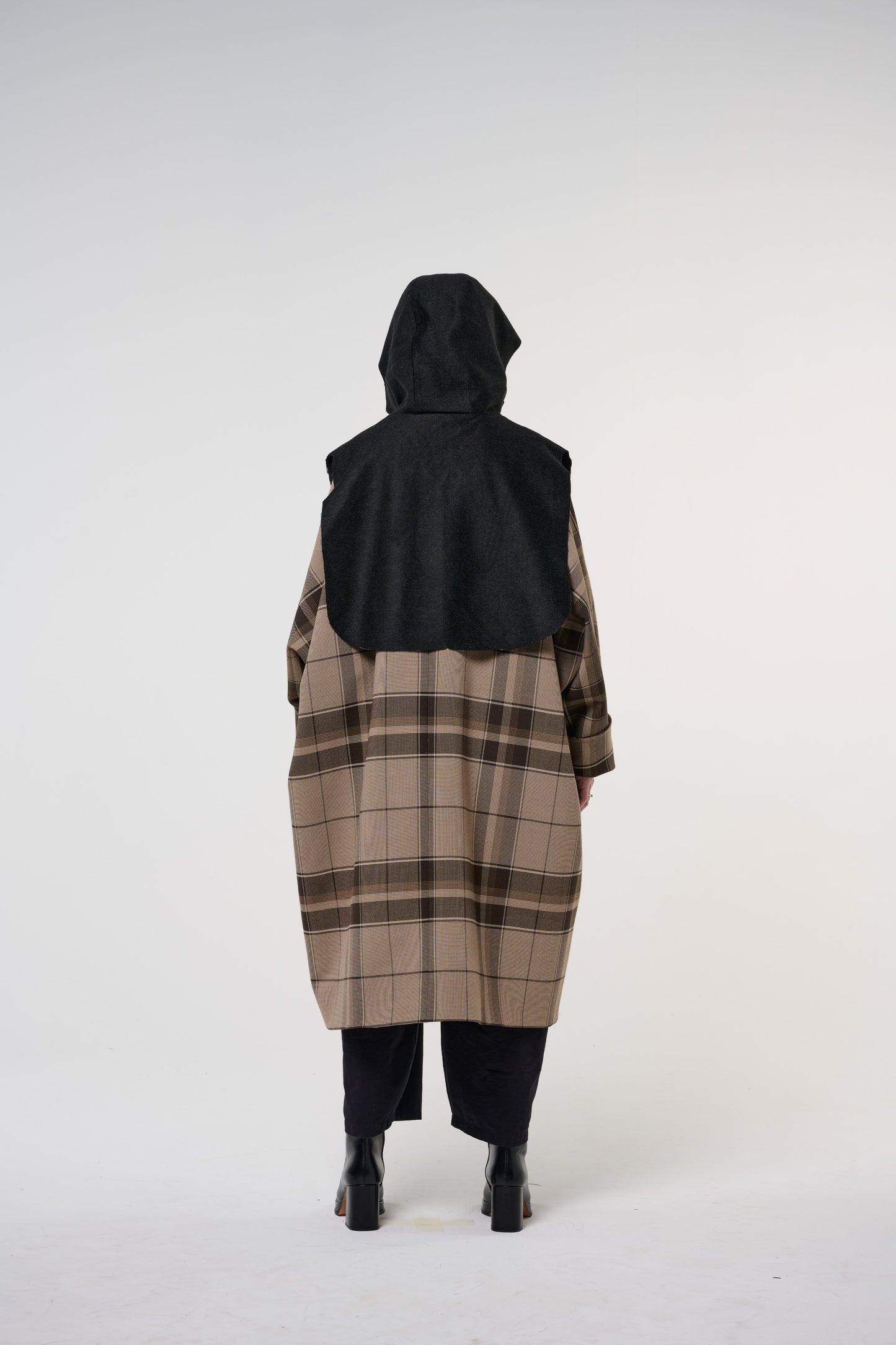 Plastron à capuche de la marque Aïdama, modèle Do en laine noire. Porté capuche relevée, par une mannequin femme et vu de dos