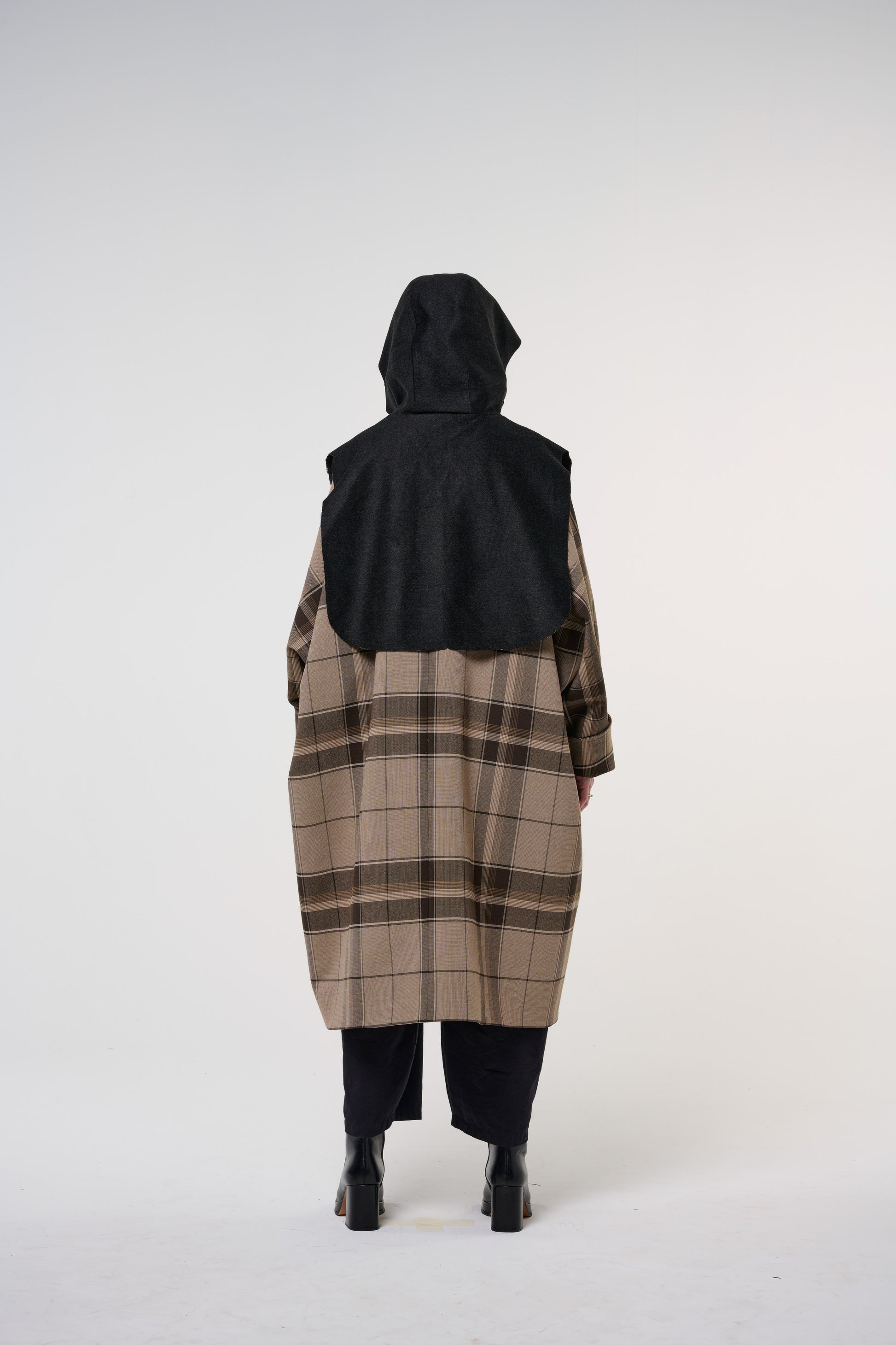 Plastron à capuche de la marque Aïdama, modèle Do en laine noire. Porté capuche relevée, par une mannequin femme et vu de dos