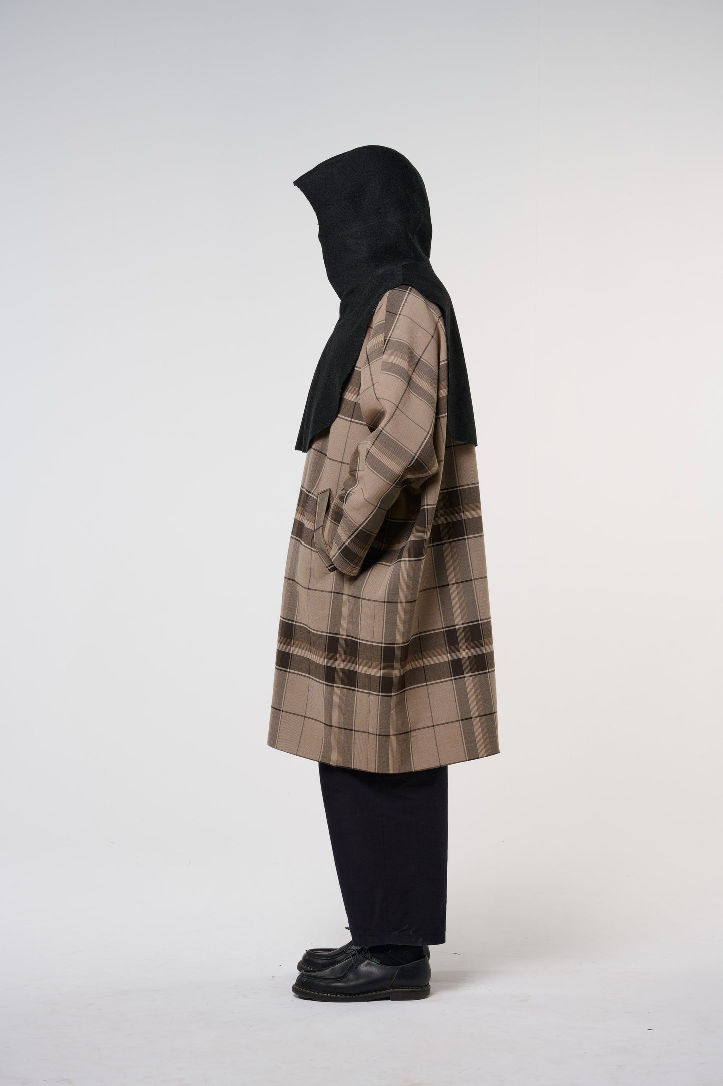 Plastron à capuche de la marque Aïdama, modèle Do en laine noire. Porté capuche relevée par un mannequin homme et vu de profil.