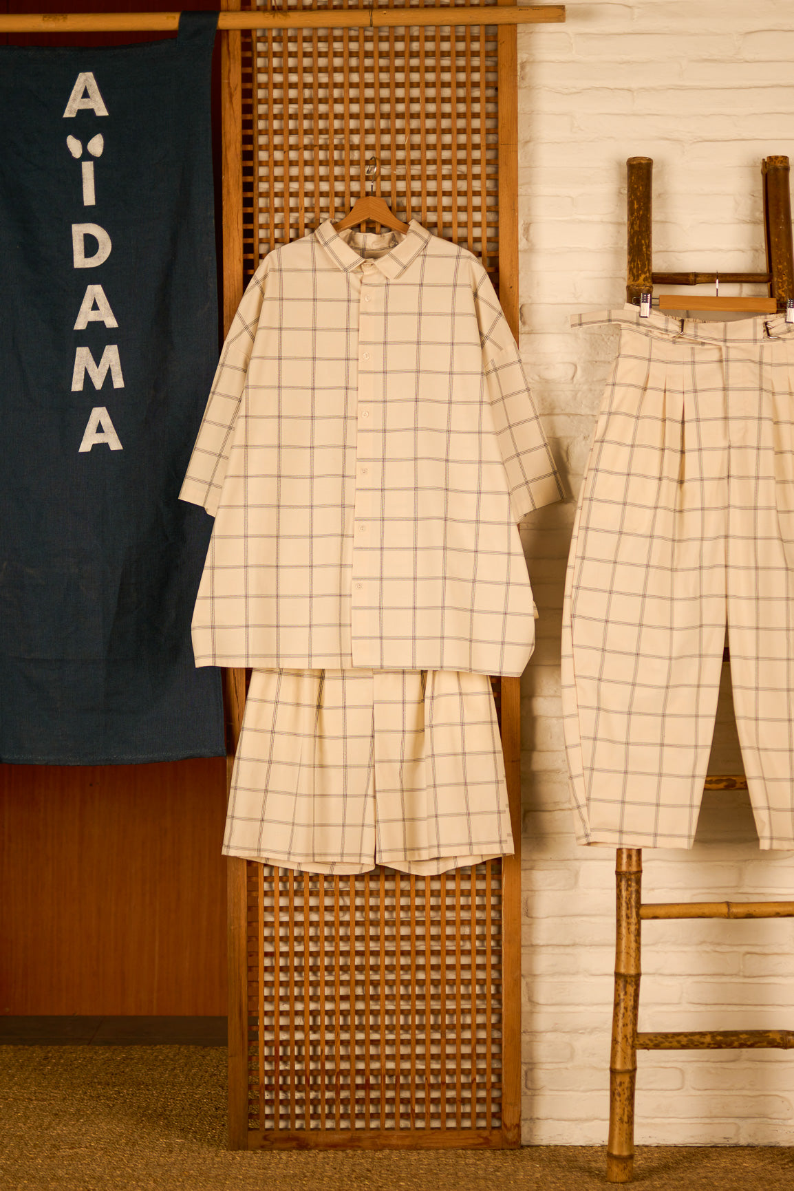 Short ballon de la marque Aïdama en coton crème à carreaux avec ceinture ajustable. Vu sur ceintre.
