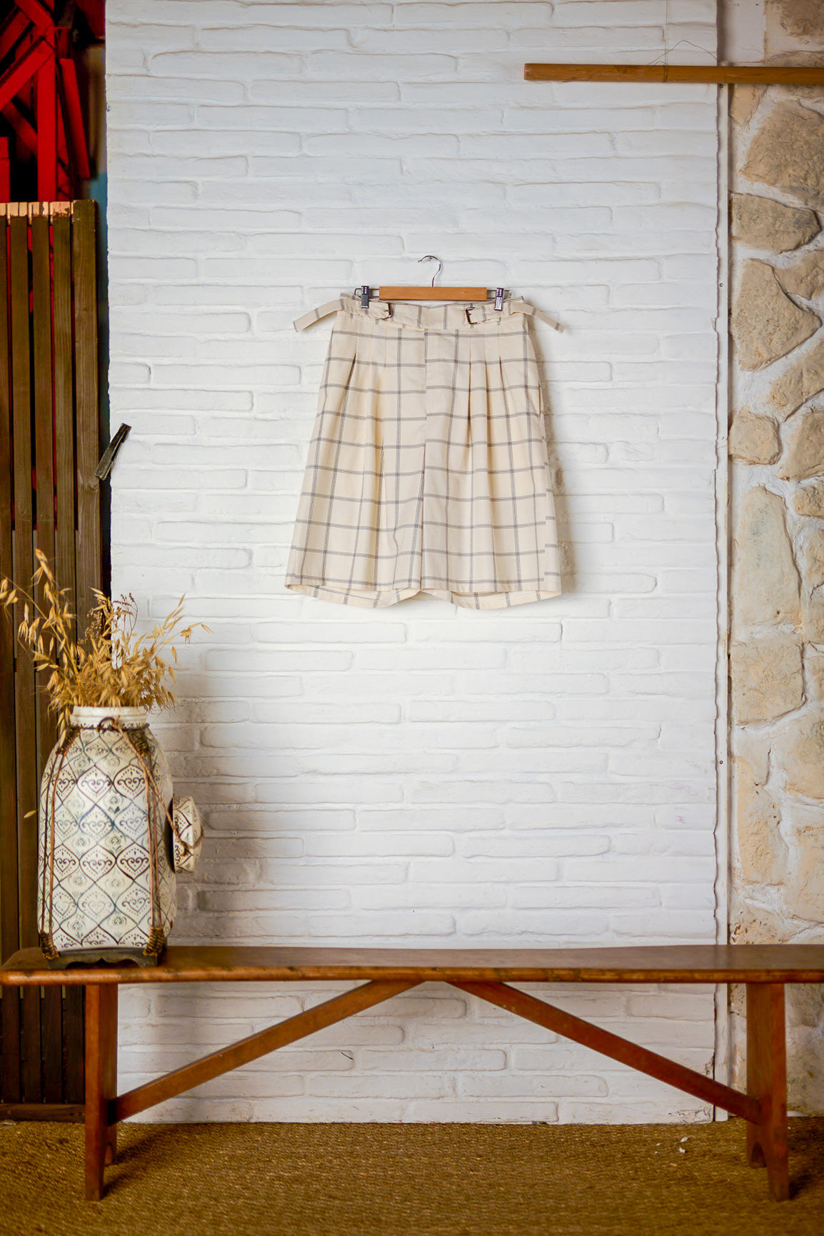 Short ballon de la marque Aïdama en coton crème à carreaux avec ceinture ajustable. Vu sur ceintre et fond blanc de face.