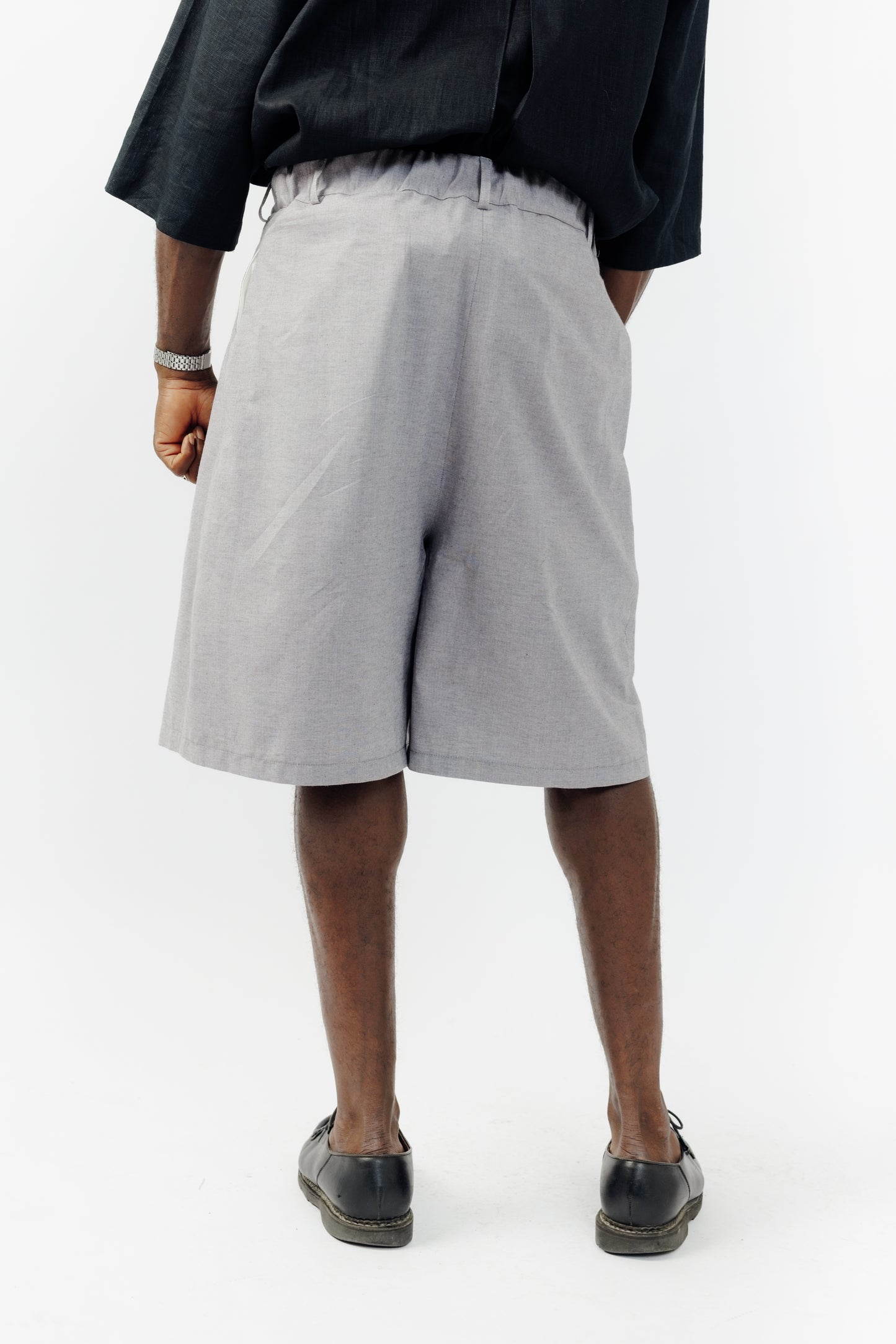 Short ballon de la marque Aïdama en coton lavande-gris à motif chevrons avec ceinture ajustable. Porté par un mannequin homme et vu de dos.