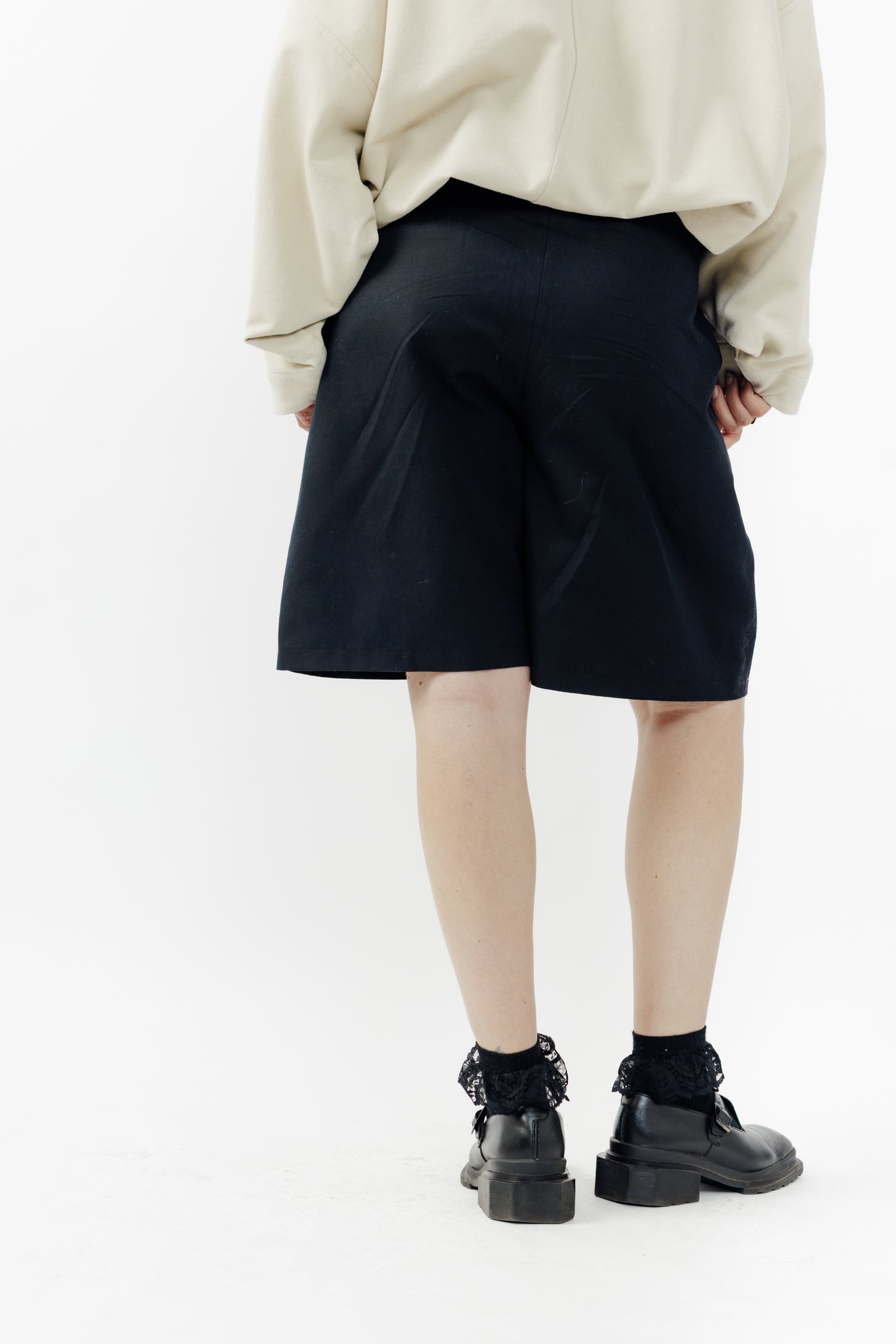 Short ballon de la marque Aïdama en coton & lin noir avec ceinture ajustable. Porté par une mannequin femme et vu de dos.
