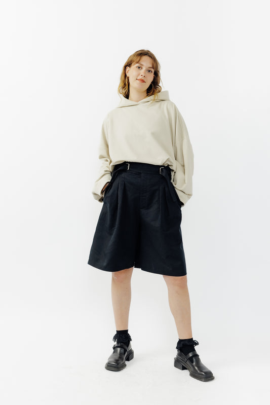 Short ballon de la marque Aïdama en coton & lin noir avec ceinture ajustable. Porté par une mannequin femme et vu de face.