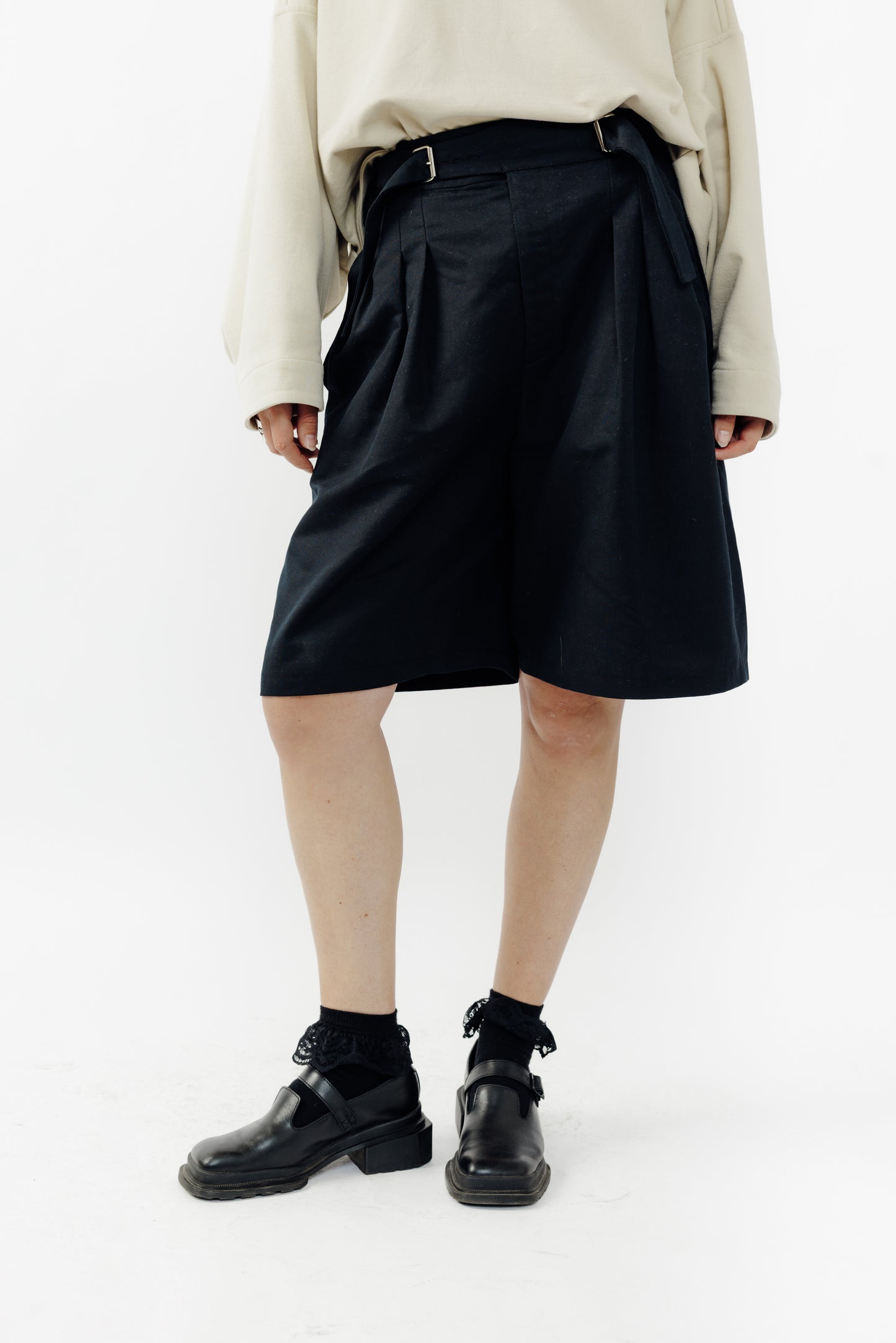 Short ballon de la marque Aïdama en coton & lin noir avec ceinture ajustable. Porté par une mannequin femme et vu de face zoomé sur les jambes.