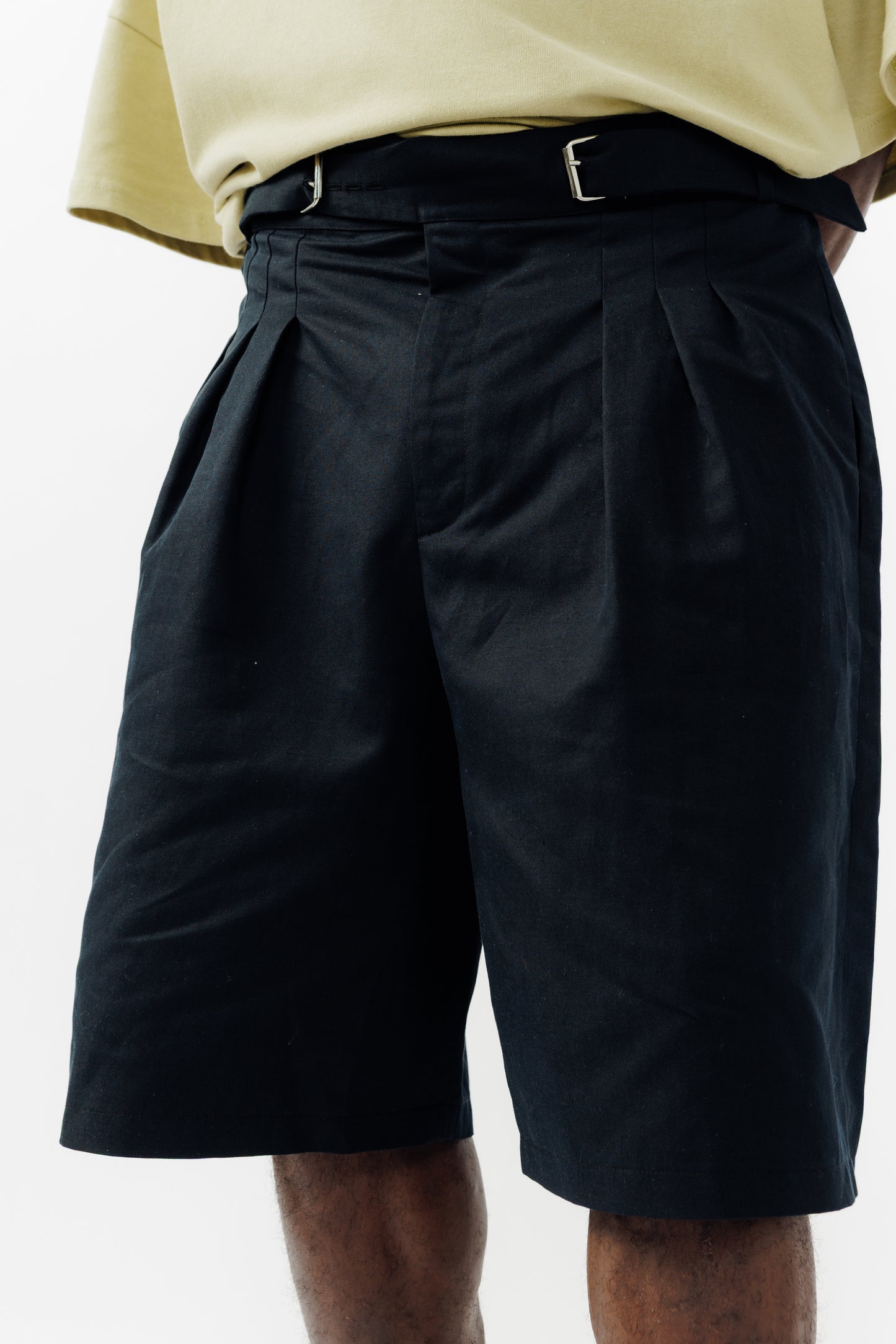 Short ballon de la marque Aïdama en coton & lin noir avec ceinture ajustable. Porté par un mannequin homme et vu de face zoomé sur la ceinture.