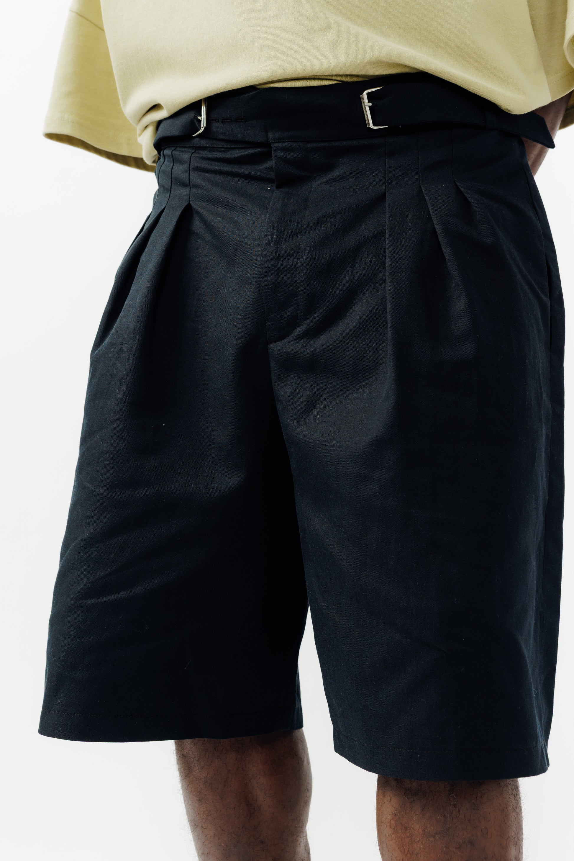 Short ballon de la marque Aïdama en coton & lin noir avec ceinture ajustable. Porté par un mannequin homme et vu de face zoomé sur la ceinture.