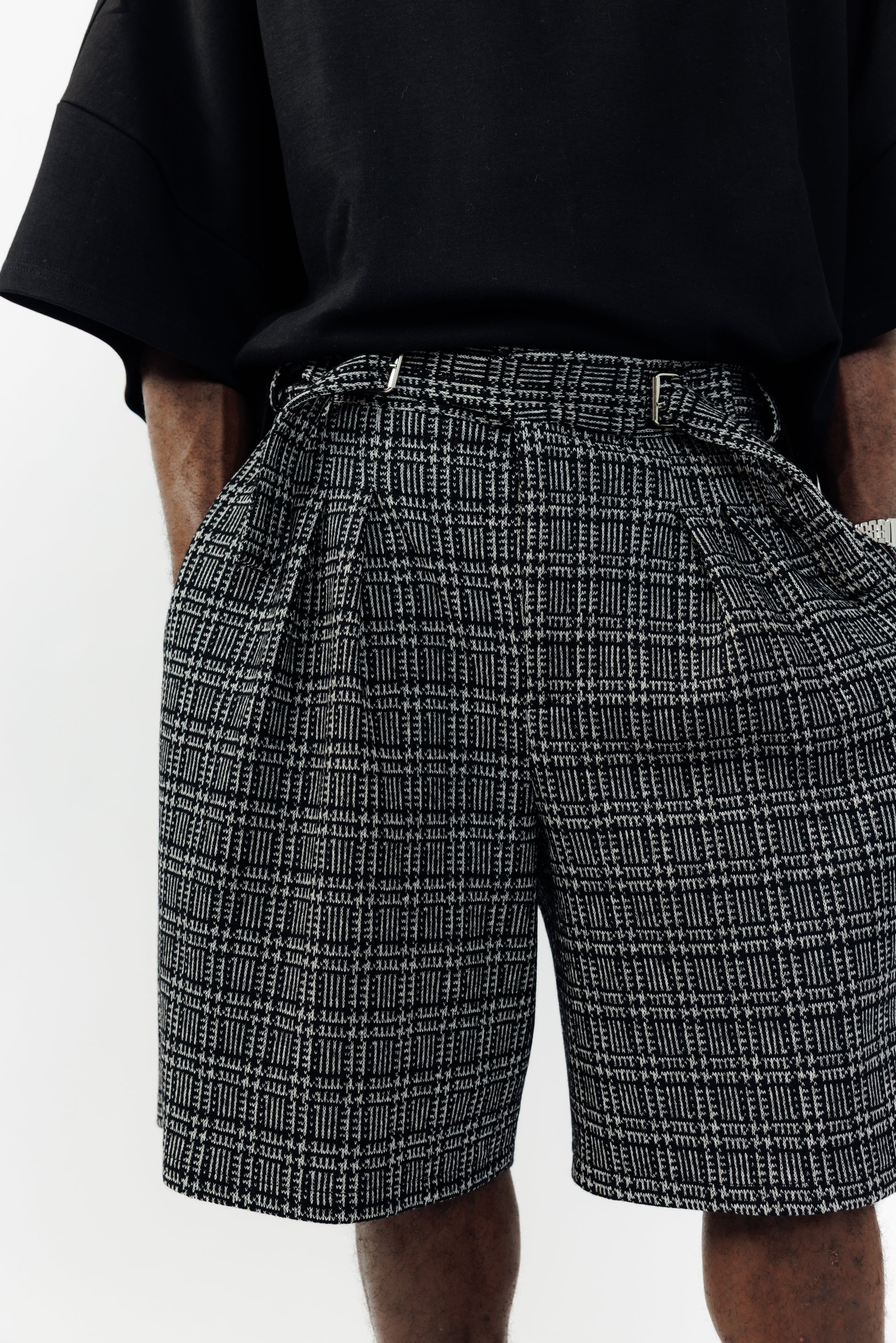 Short ballon de la marque Aïdama en laine à motif géométriques noirs et blancs avec ceinture ajustable. Porté par un mannequin homme et vu de face zoomé sur la ceinture.