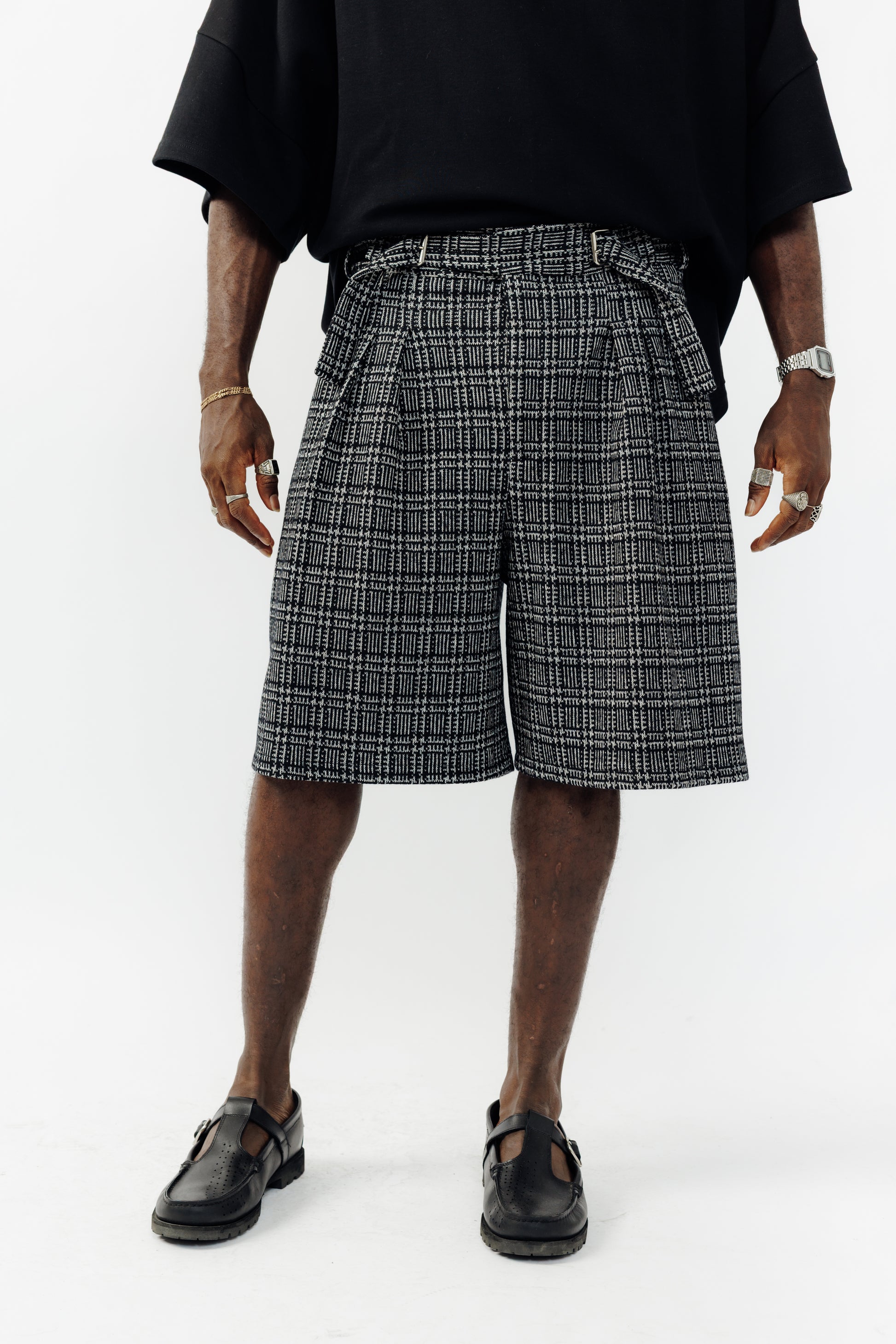 Short ballon de la marque Aïdama en laine à motif géométriques noirs et blancs avec ceinture ajustable. Porté par un mannequin homme et vu zoomé sur les jambes.
