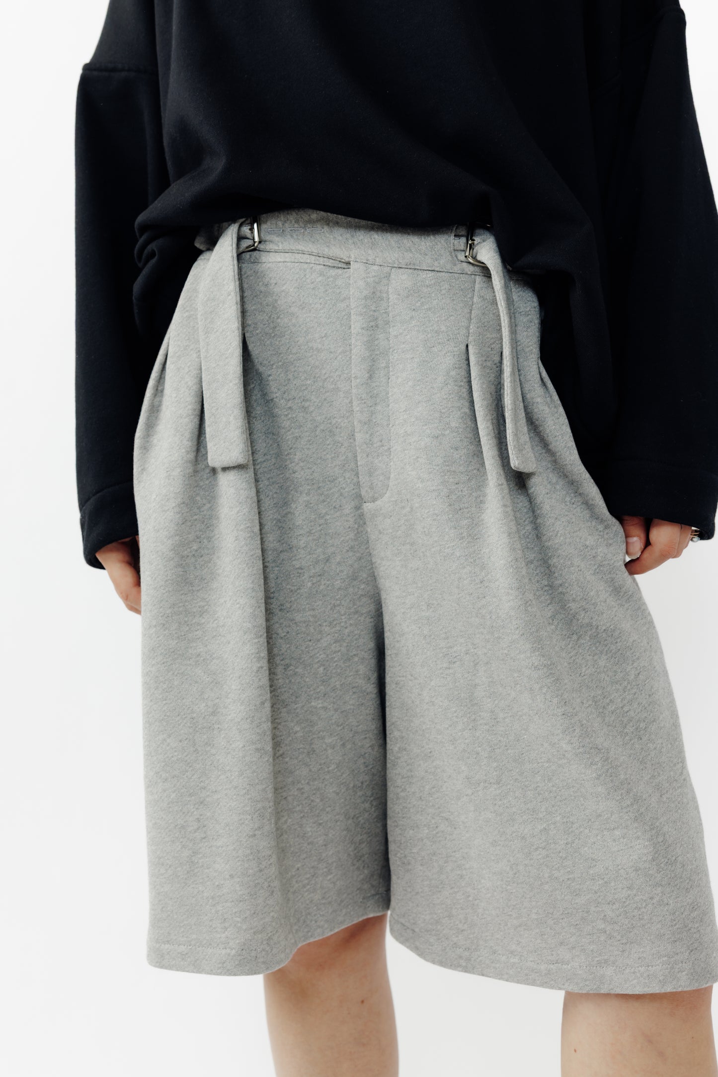 Short ballon de la marque Aïdama en laine à motif géométriques noirs et blancs avec ceinture ajustable. Porté par une mannequin femme et vu de face zoomé sur les jambes.