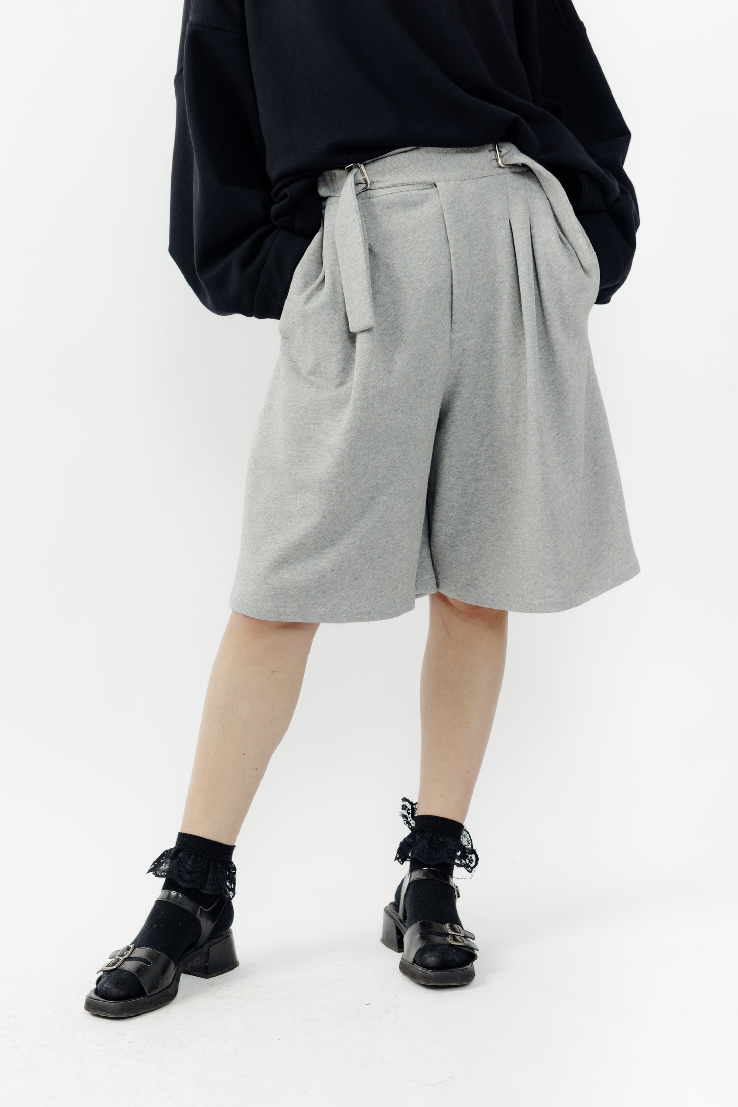Short ballon de la marque Aïdama en laine à motif géométriques noirs et blancs avec ceinture ajustable. Porté par une mannequin femme et vu de face zoomé sur les jambes.