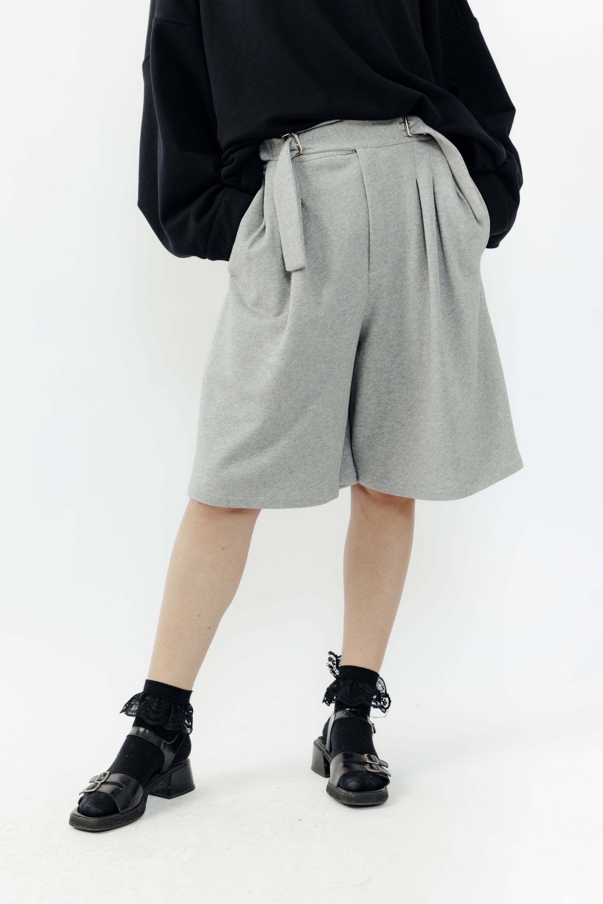 Short ballon de la marque Aïdama en laine à motif géométriques noirs et blancs avec ceinture ajustable. Porté par une mannequin femme et vu de face zoomé sur les jambes.