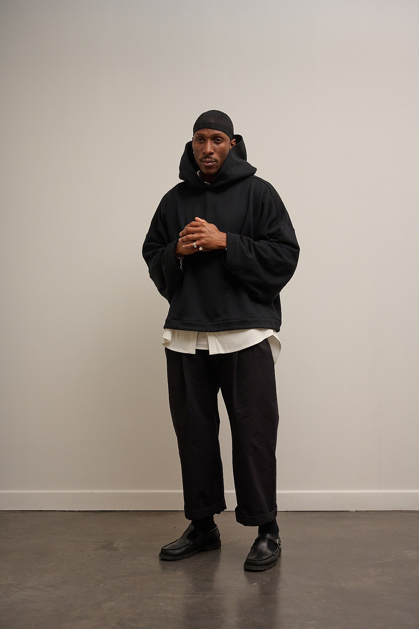 Sweat à capuche oversize Mino de la marque Aïdama en molleton de coton noir. Porté par un mannequin homme et vu de face.