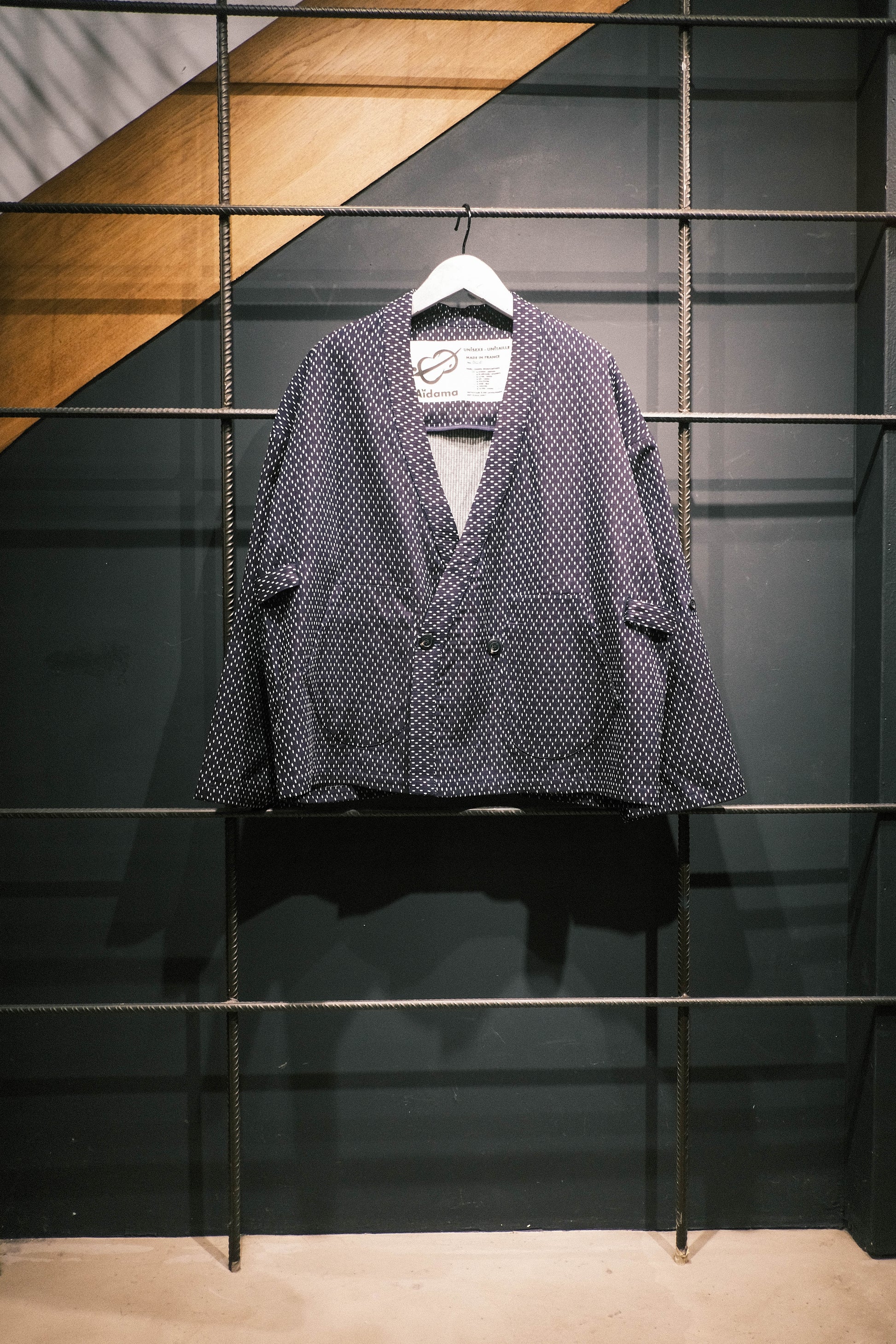 Veste croisée à col kimono de la marque Aïdama, modèle Samue en coton japonais bleu brodé de points Sashiko. Vue de face sur ceintre.