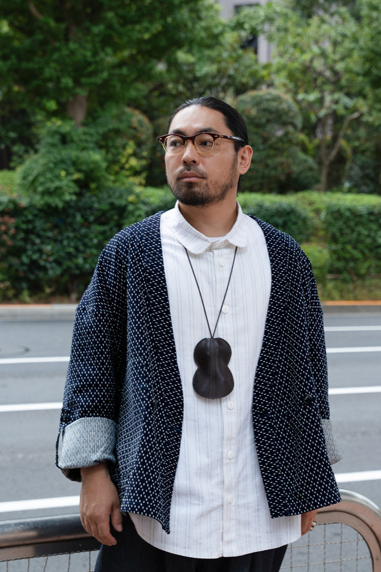 Veste croisée à col kimono de la marque Aïdama, modèle Samue en coton japonais bleu brodé de points Sashiko. Portée ouverte par un mannequin homme et vue de face. 