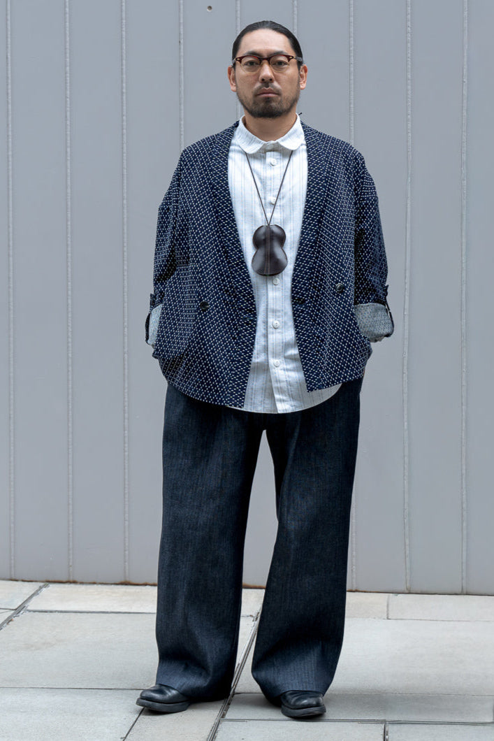 Veste croisée à col kimono de la marque Aïdama, modèle Samue en coton japonais bleu brodé de points Sashiko. Portée ouverte par un mannequin homme et vue de face. 