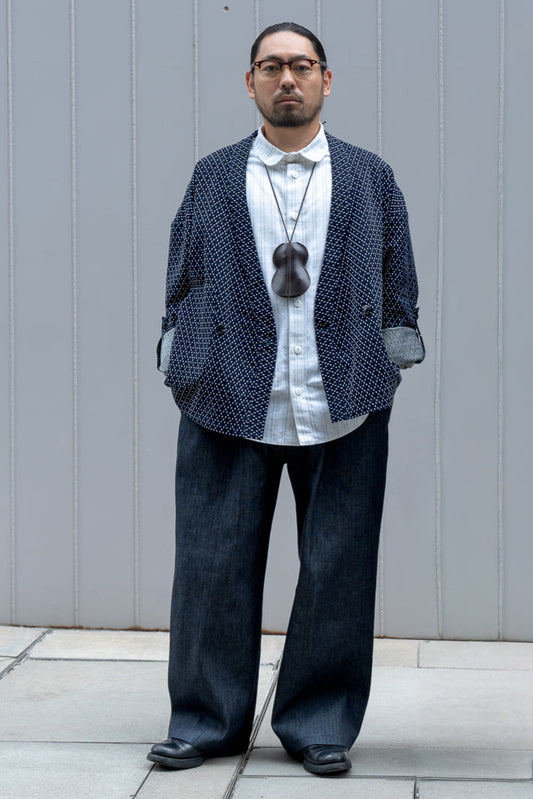 Veste croisée à col kimono de la marque Aïdama, modèle Samue en coton japonais bleu brodé de points Sashiko. Portée ouverte par un mannequin homme et vue de face. 