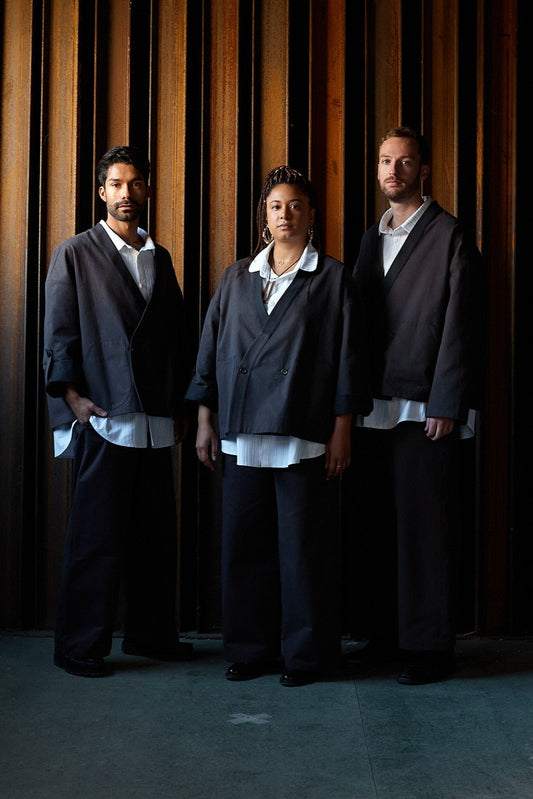Veste croisée à col kimono de la marque Aïdama, modèle samue en toile de coton brun à rayures tennis. Portée fermée par deux mannequins hommes et une femme vues de face. 
