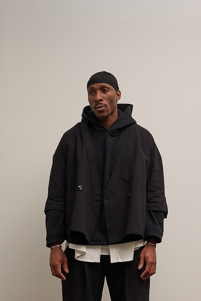 Veste croisée à col kimono de la marque Aïdama, modèle samue en mélange de coton et papier japonais noir. Portée ouverte par un mannequin homme et vue de face.