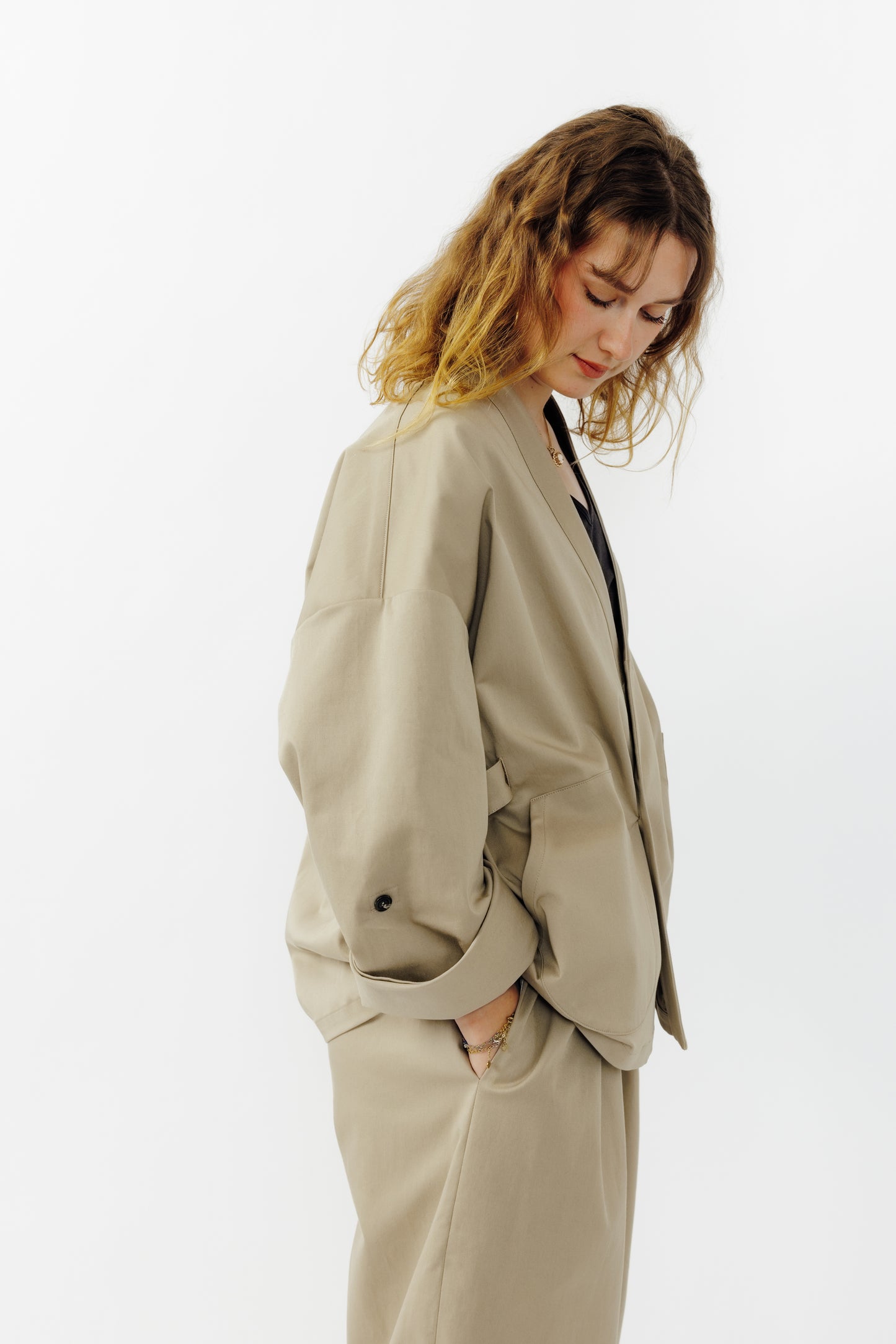 Veste croisée à col kimono de la marque Aïdama, modèle samue en gabardine de coton beige. Portée ouverte par une mannequin femme et vu de profil.
