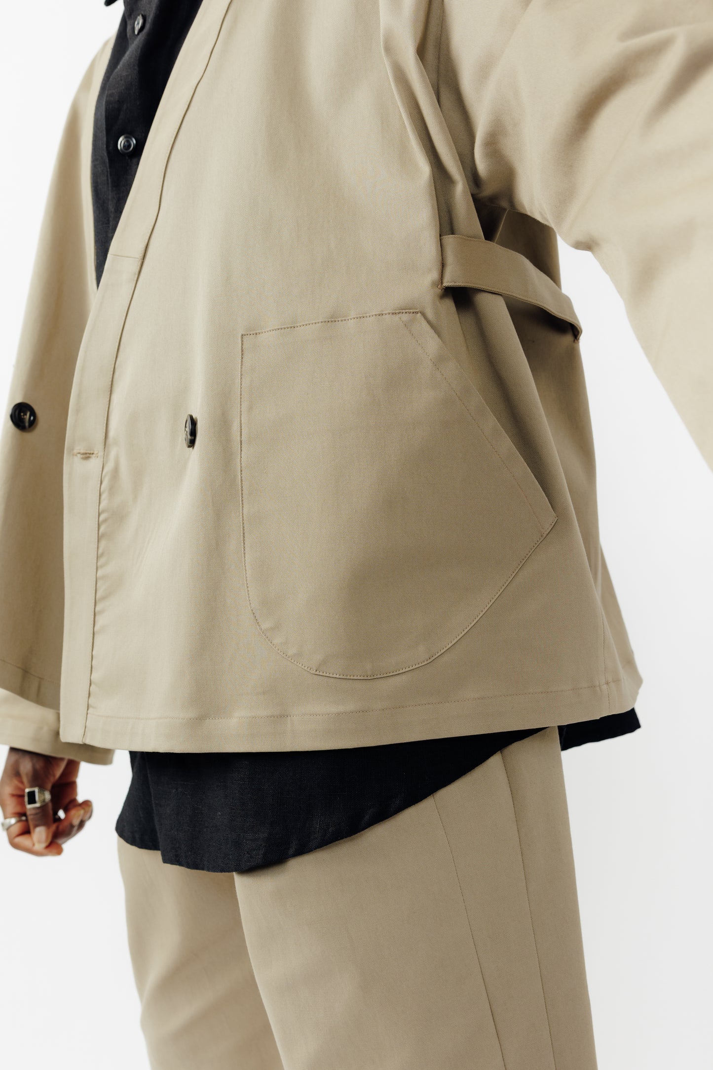 Veste croisée à col kimono de la marque Aïdama, modèle samue en gabardine de coton beige. Portée ouverte par un mannequin homme et vu de face zoomé sur la poche.