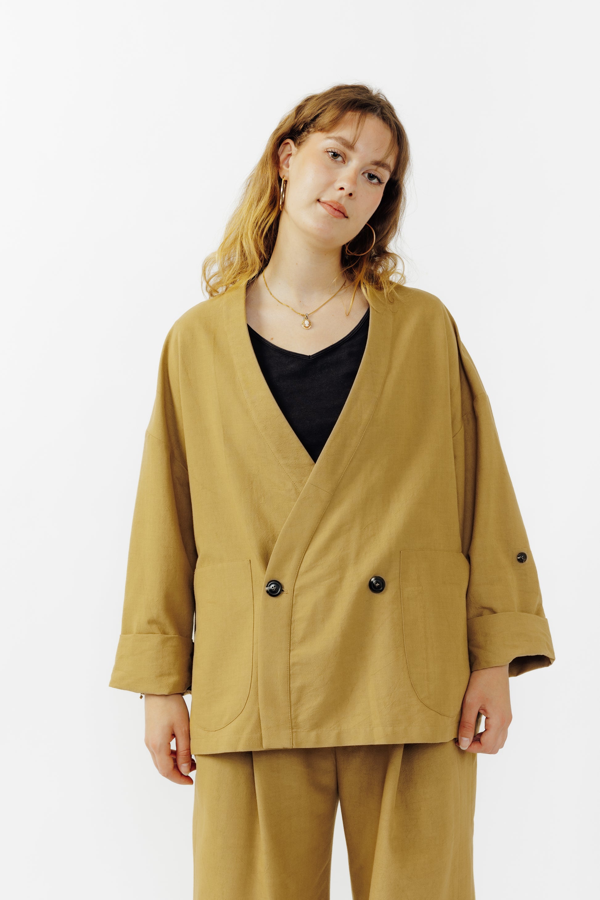 Veste croisée à col kimono de la marque Aïdama, modèle samue en crêpe de laine et coton sable. Portée fermée par une mannequin femme et vu de face. 