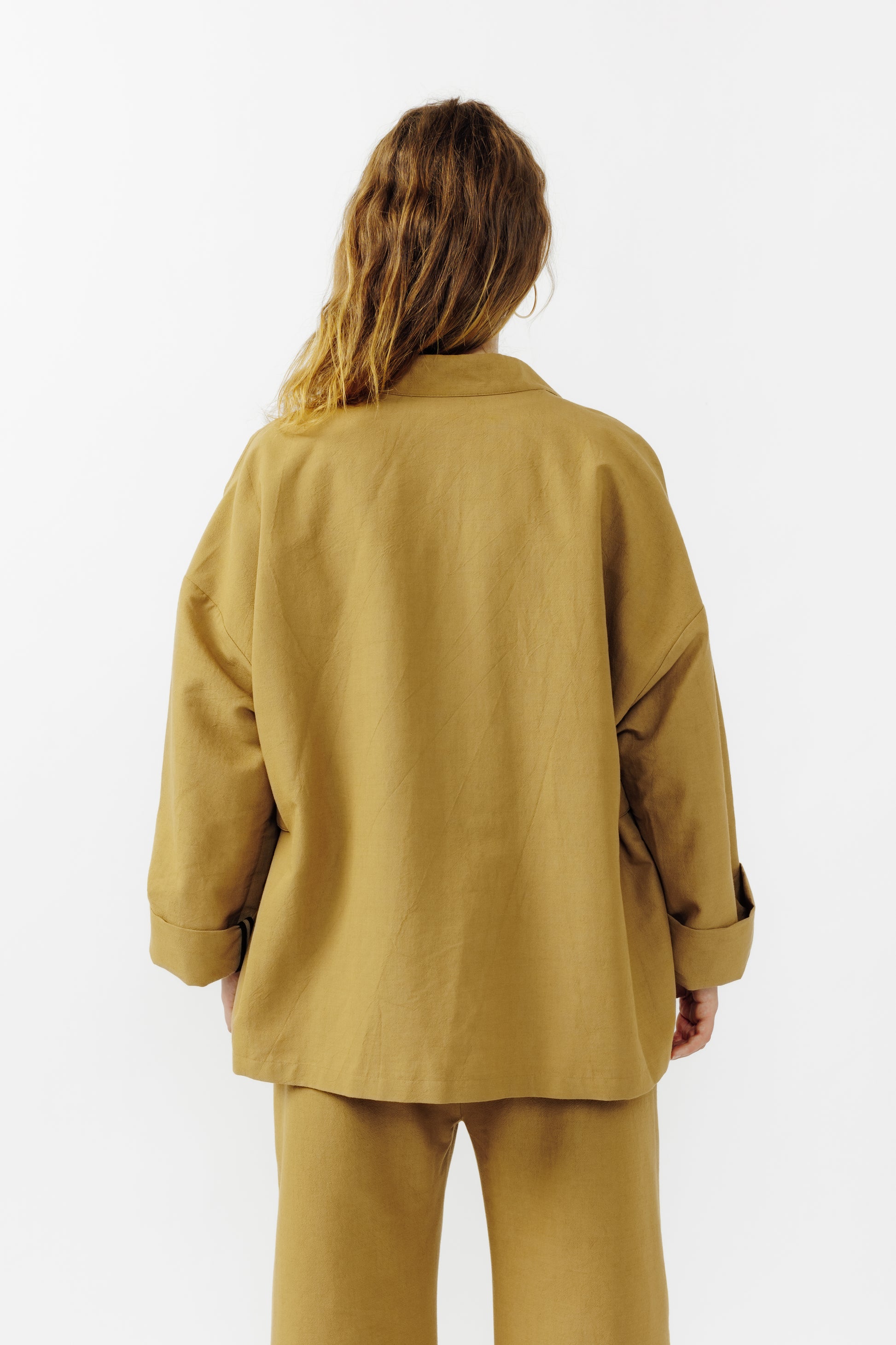 Veste croisée à col kimono de la marque Aïdama, modèle samue en crêpe de laine et coton sable. Portée fermée par une mannequin femme et vu de dos.