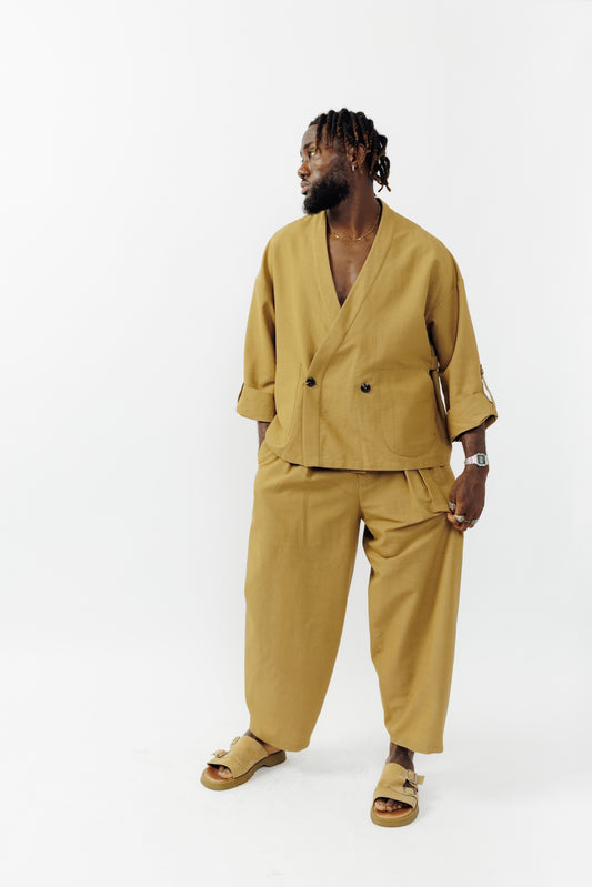 Veste croisée à col kimono de la marque Aïdama, modèle samue en crêpe de laine et coton sable. Portée fermée par un mannequin homme et vu de face. 