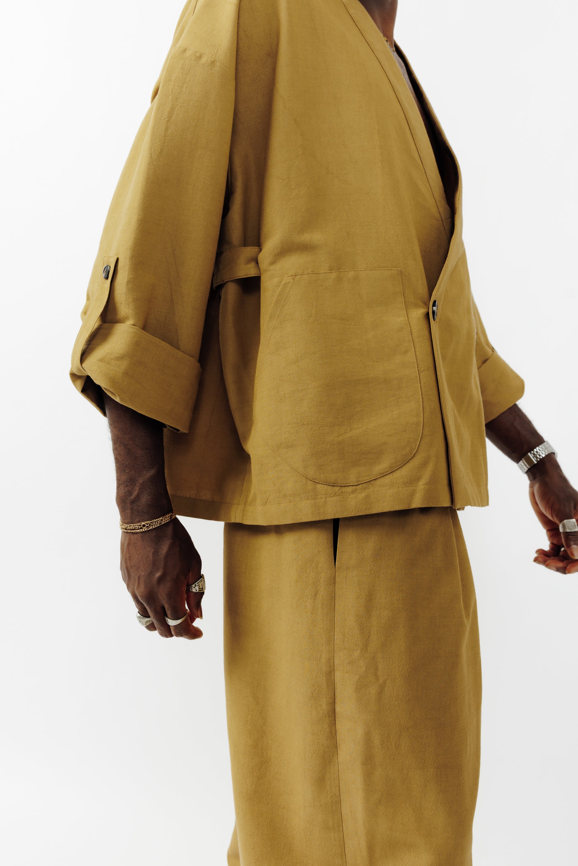 Veste croisée à col kimono de la marque Aïdama, modèle samue en crêpe de laine et coton sable. Portée fermée par un mannequin homme et vu de profil.