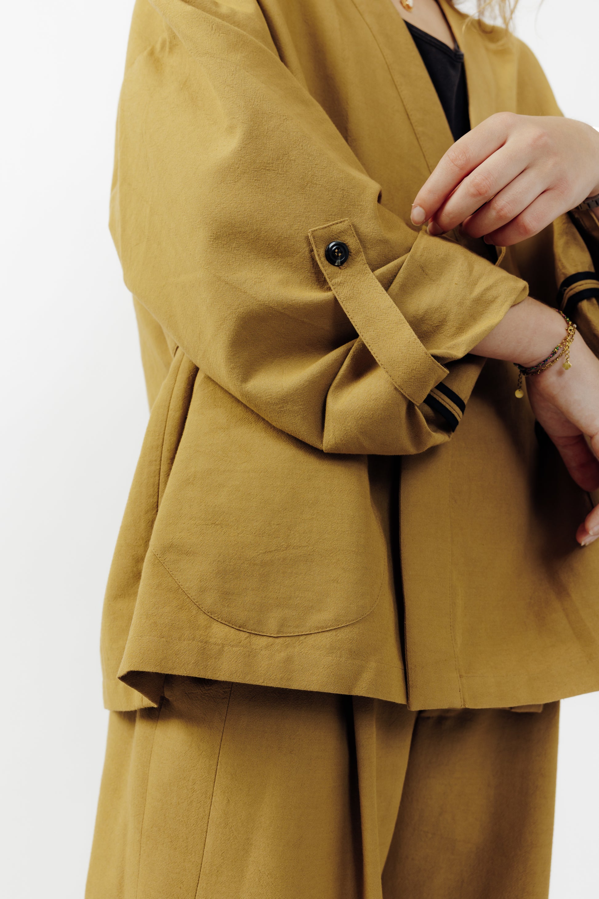 Veste croisée à col kimono de la marque Aïdama, modèle samue en crêpe de laine et coton sable. Portée ouverte par une mannequin femme et vue zoomée sur la manche. 