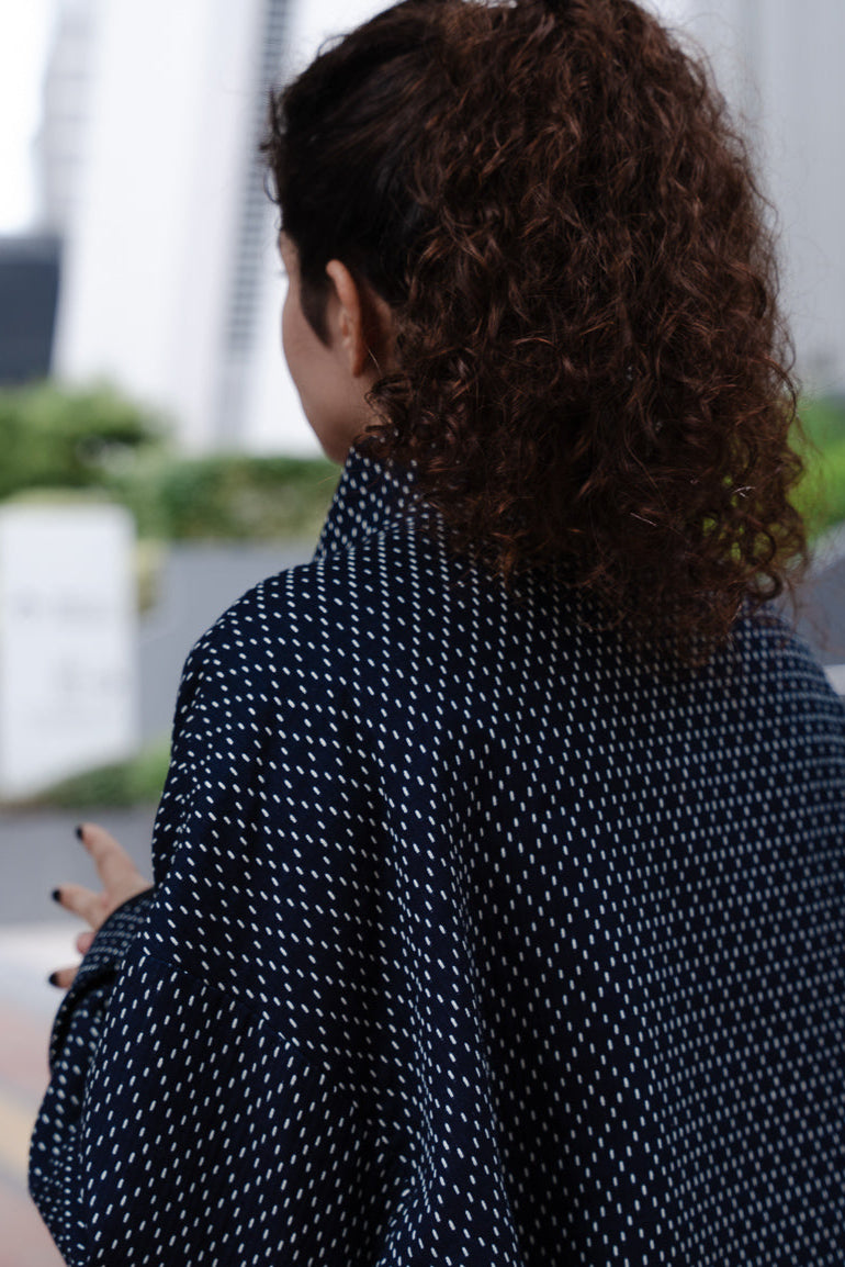 Veste oversize à col arrondi de la marque Aïdama, modèle Gunbai en coton japonais bleu brodé de points Sashiko. Portée par une mannequin femme et vue de dos. 