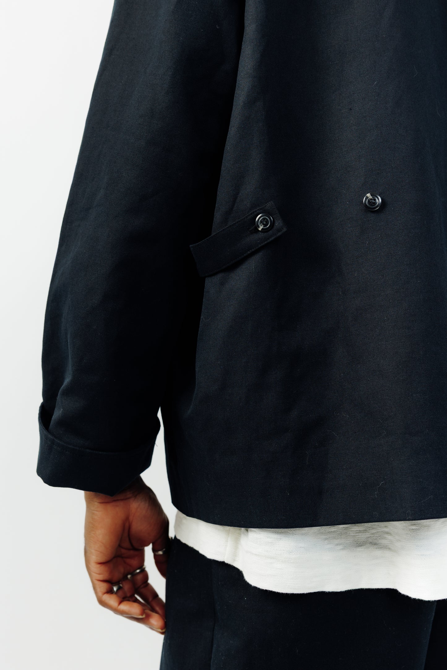 Veste oversize à col arrondi de la marque Aïdama, modèle Gunbai en coton & lin noir. Portée fermée par un mannequin homme et vue de dos zoomée sur la sangle de serrage.