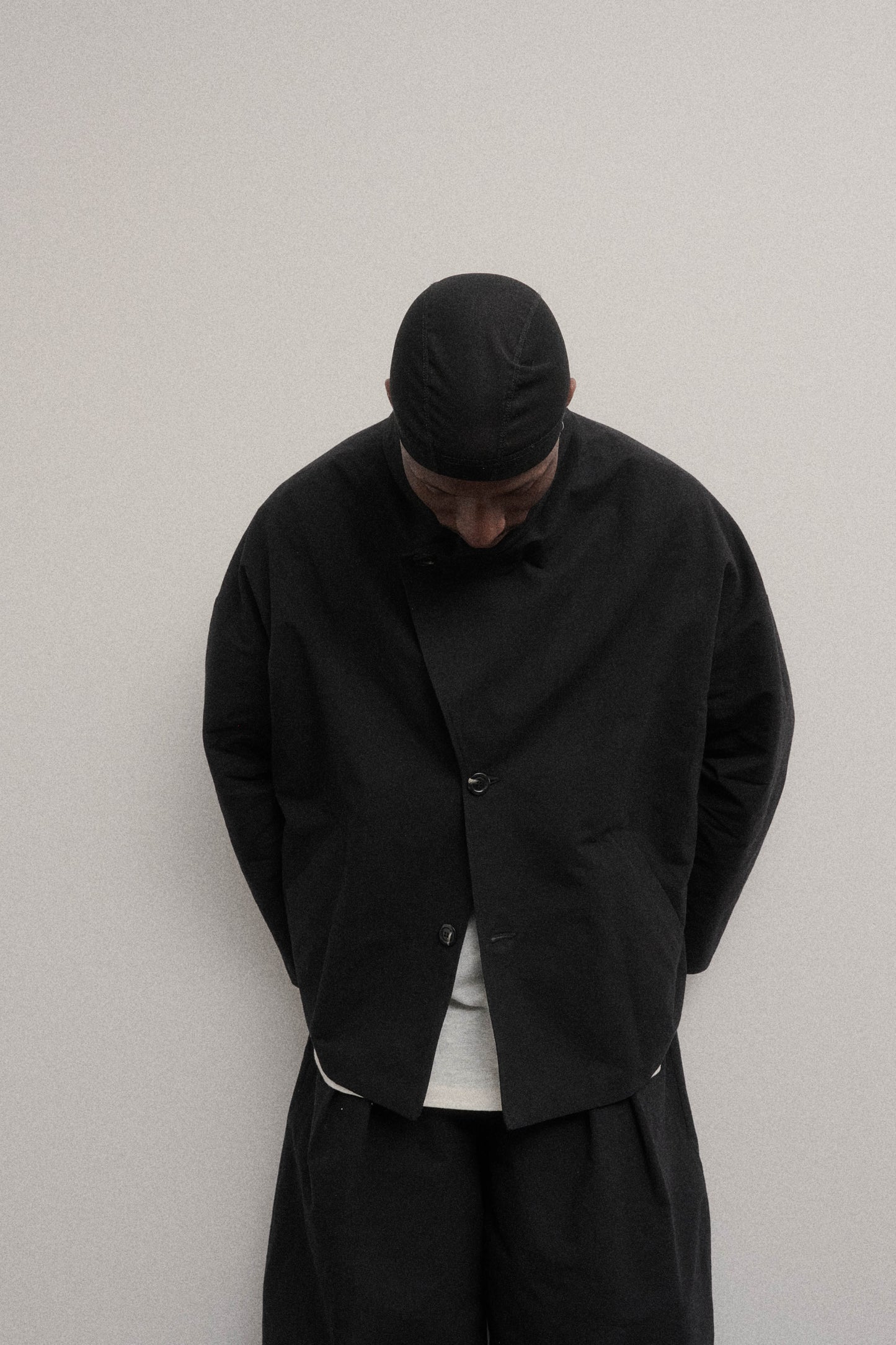 Veste oversize à col arrondi de la marque Aïdama en mélange de coton et papier japonais noir. Portée fermée par un mannequin homme et vu de face.