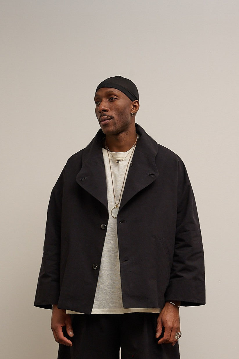 Veste oversize à col arrondi de la marque Aïdama en mélange de coton et papier japonais noir. Portée ouverte par un mannequin homme et vu de face.