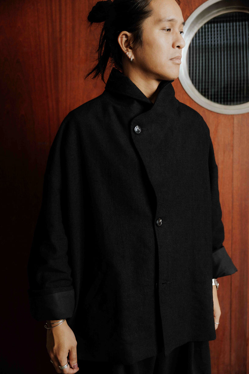 Veste oversize à col arrondi de la marque Aïdama, modèle Gunbai en laine et lin noir Portée fermée par un mannequin homme et vue de face.