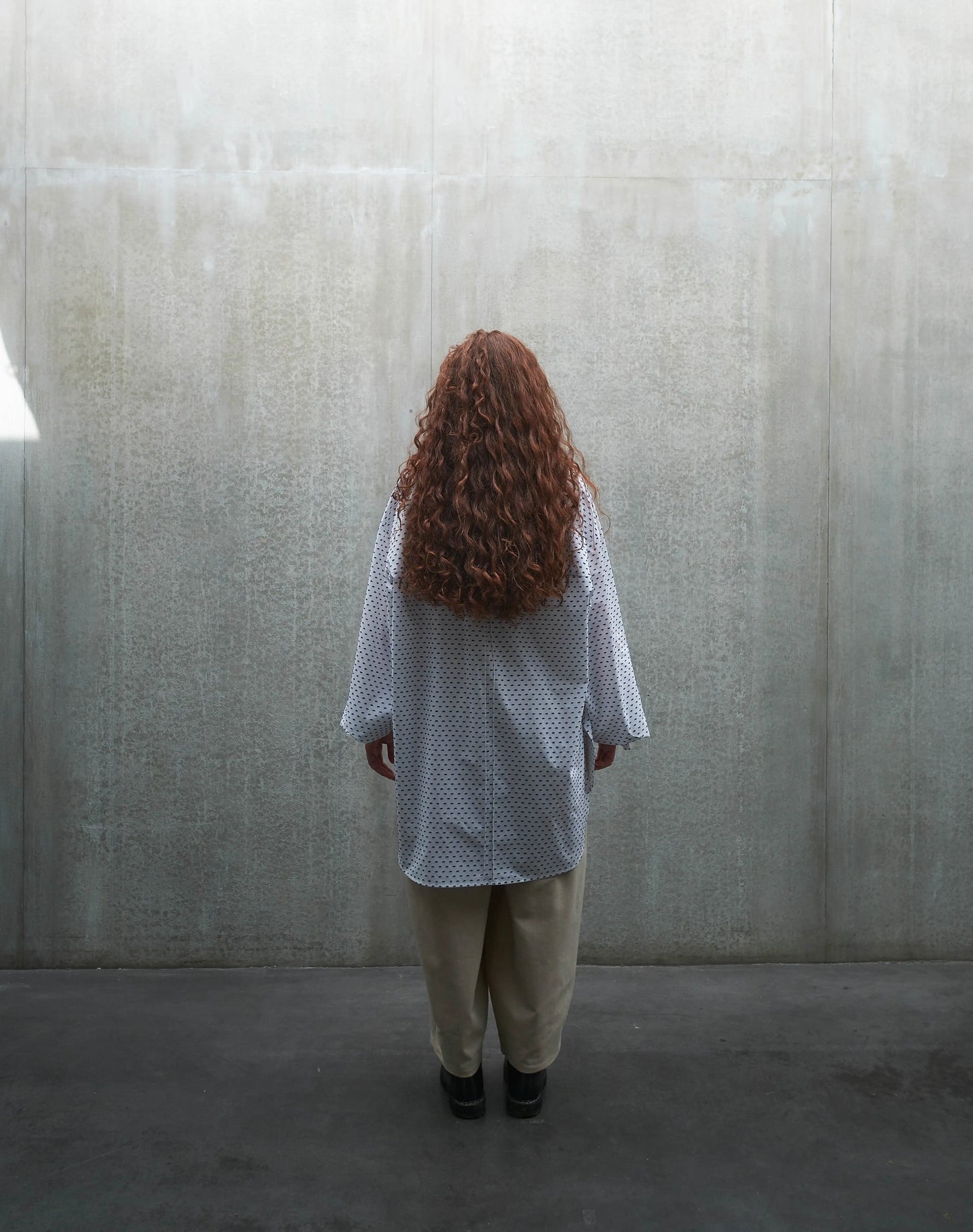 Chemise oversize à manches longues et col rond Aïdama modèle Ao en coton blanc à pois bleus. Portée par une mannequin femme et vue de dos.