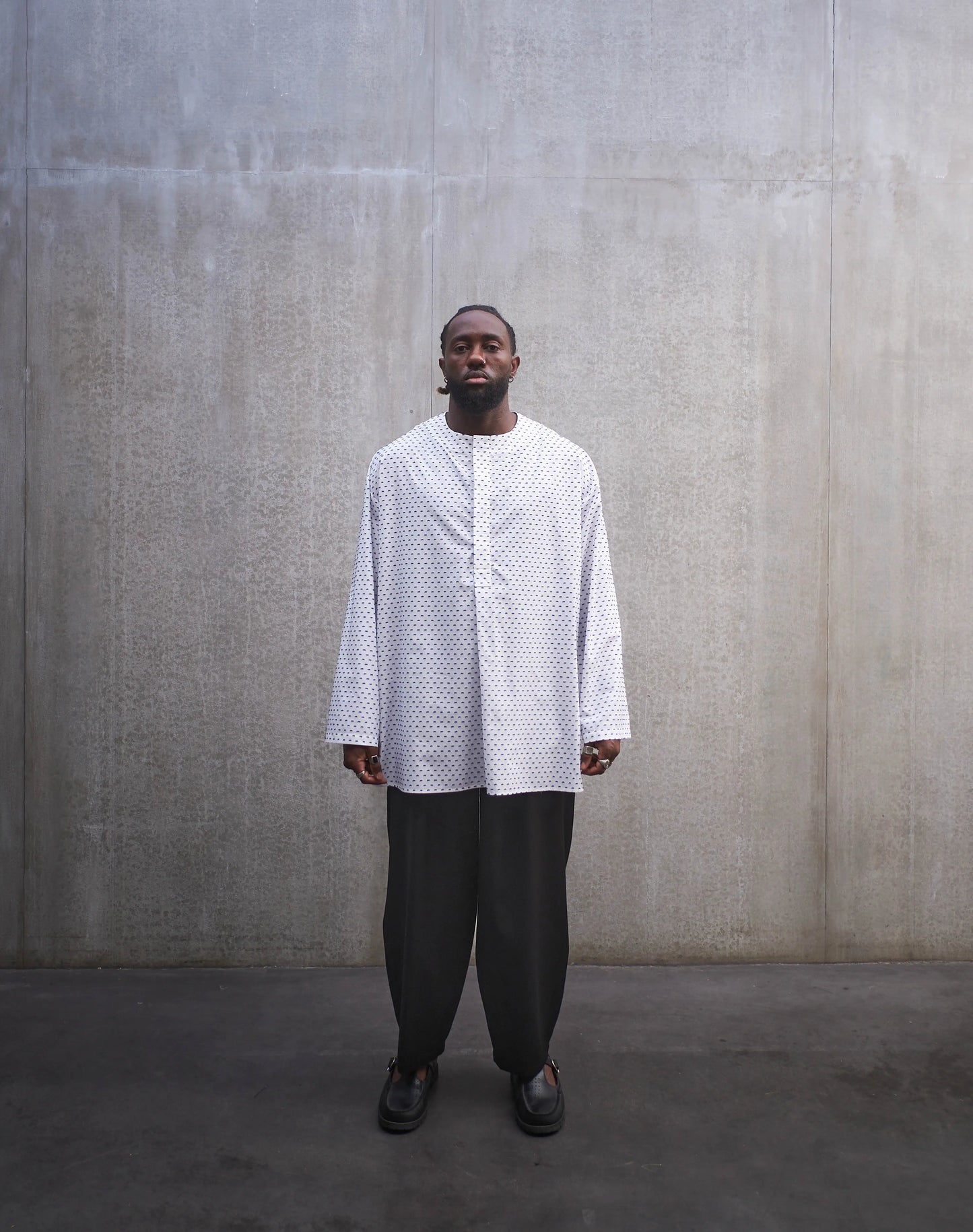 Chemise oversize à manches longues et col rond Aïdama modèle Ao en coton blanc à pois bleus. Portée par un mannequin homme et vue de face.