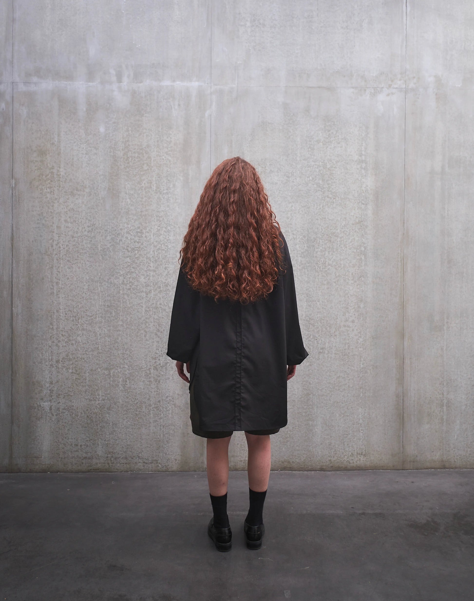 Chemise oversize à manche longue et col rond Aïdama modèle Ao en popeline de coton noir. Portée par une mannequin femme et vue de dos.