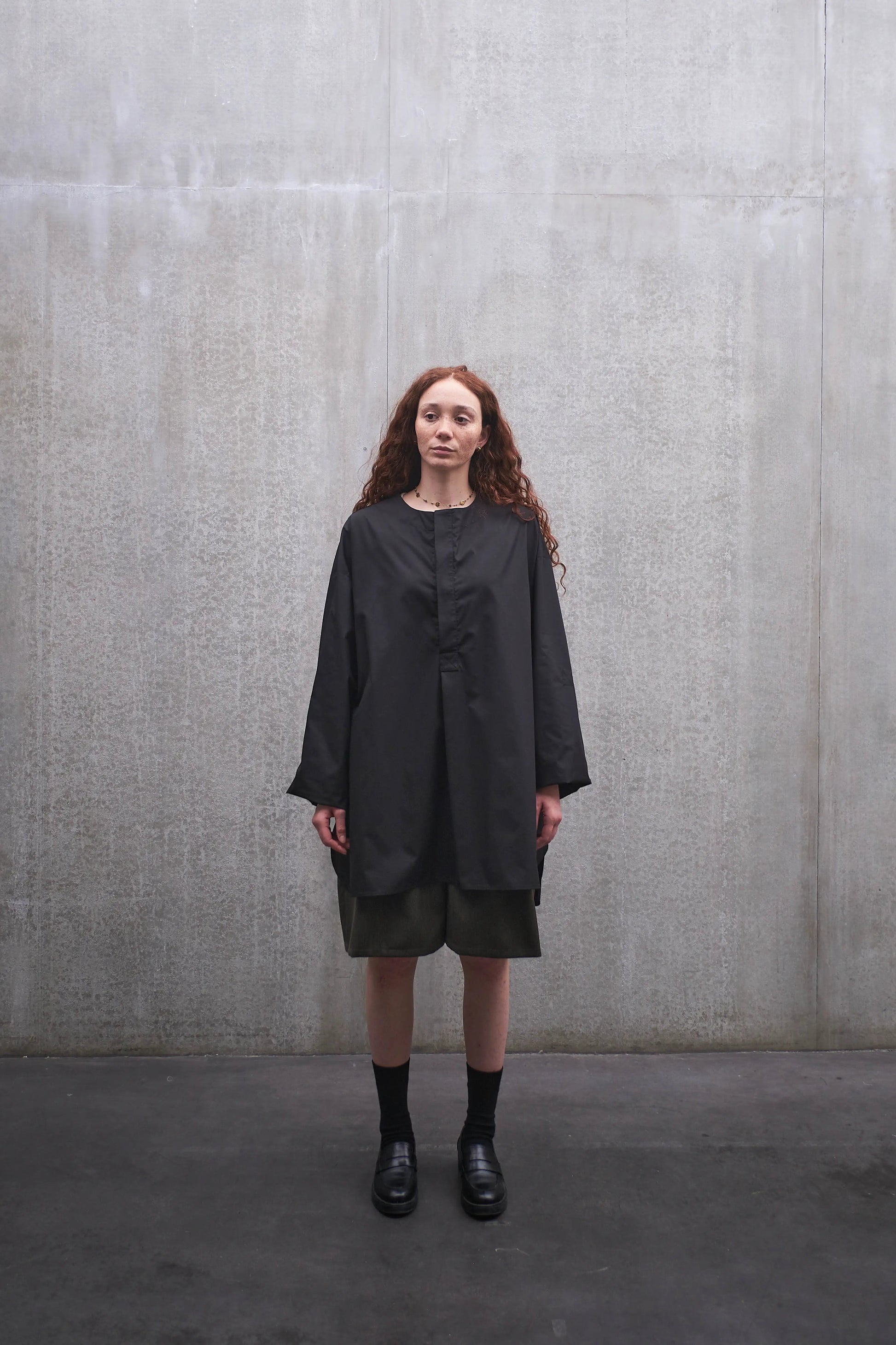 Chemise oversize à manche longue et col rond Aïdama modèle Ao en popeline de coton noir. Portée par une mannequin femme et vue de face.