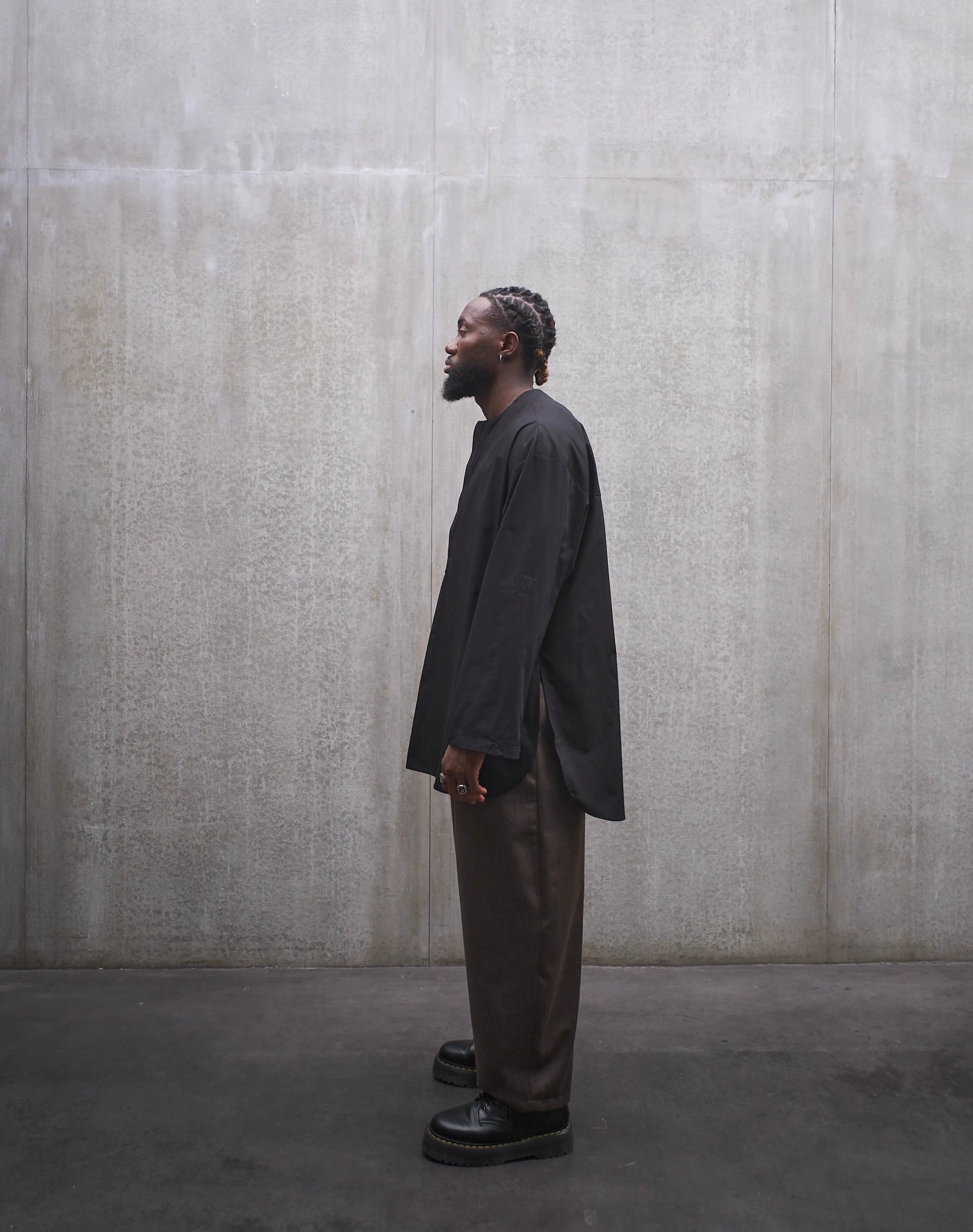 Chemise oversize à manche longue et col rond Aïdama modèle Ao en popeline de coton noir. Portée par un mannequin homme et vue de profil.