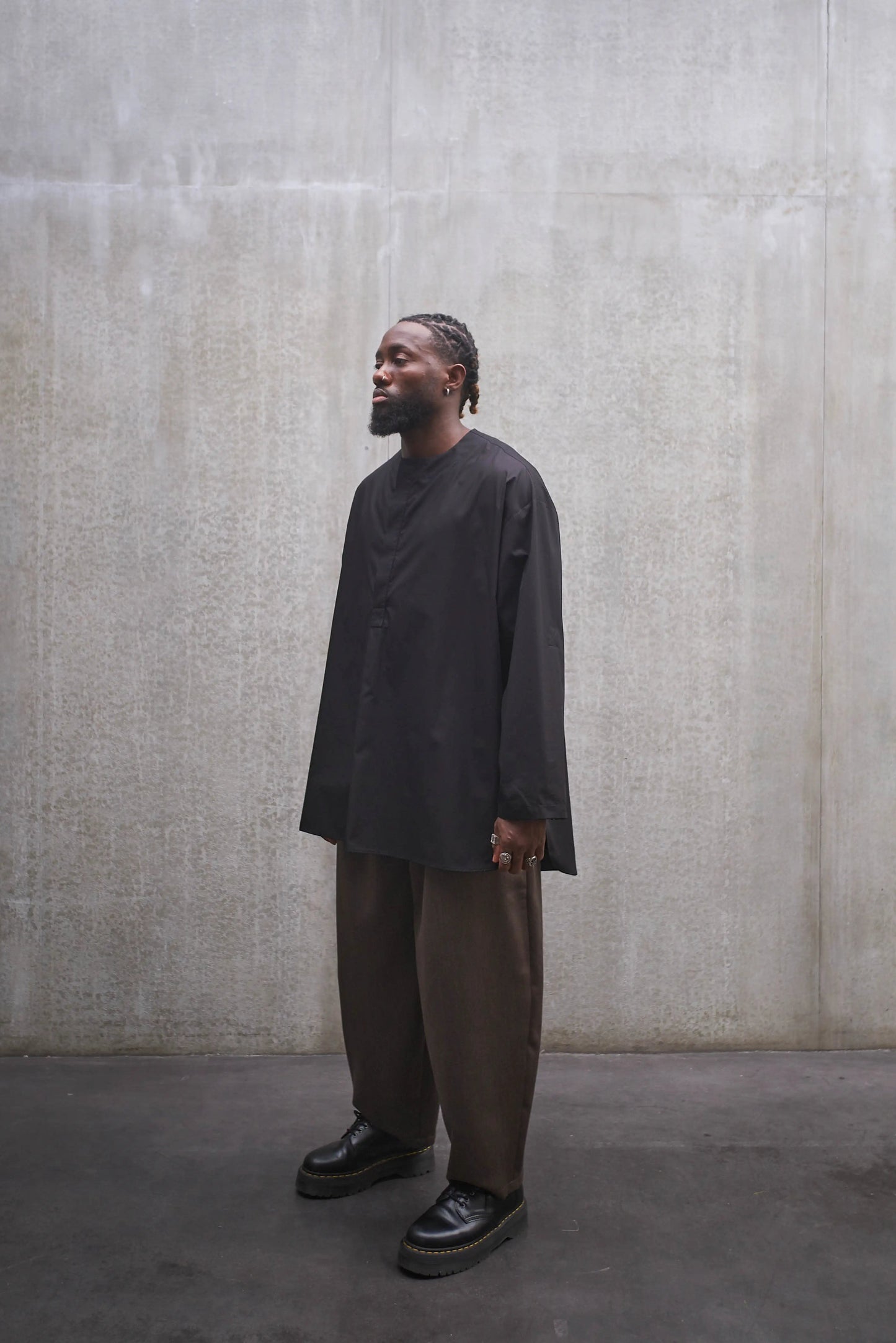 Chemise à manche longue et col rond Aïdama modèle Ao en popeline de coton noir. Portée par un mannequin homme et vue de profil.
