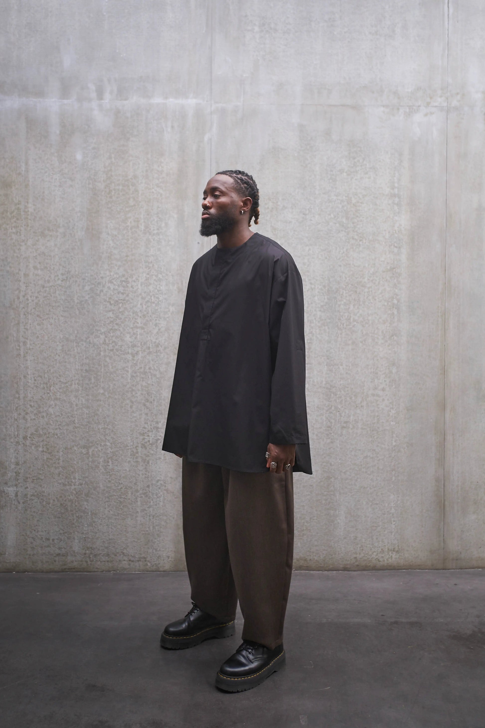 Chemise à manche longue et col rond Aïdama modèle Ao en popeline de coton noir. Portée par un mannequin homme et vue de profil.