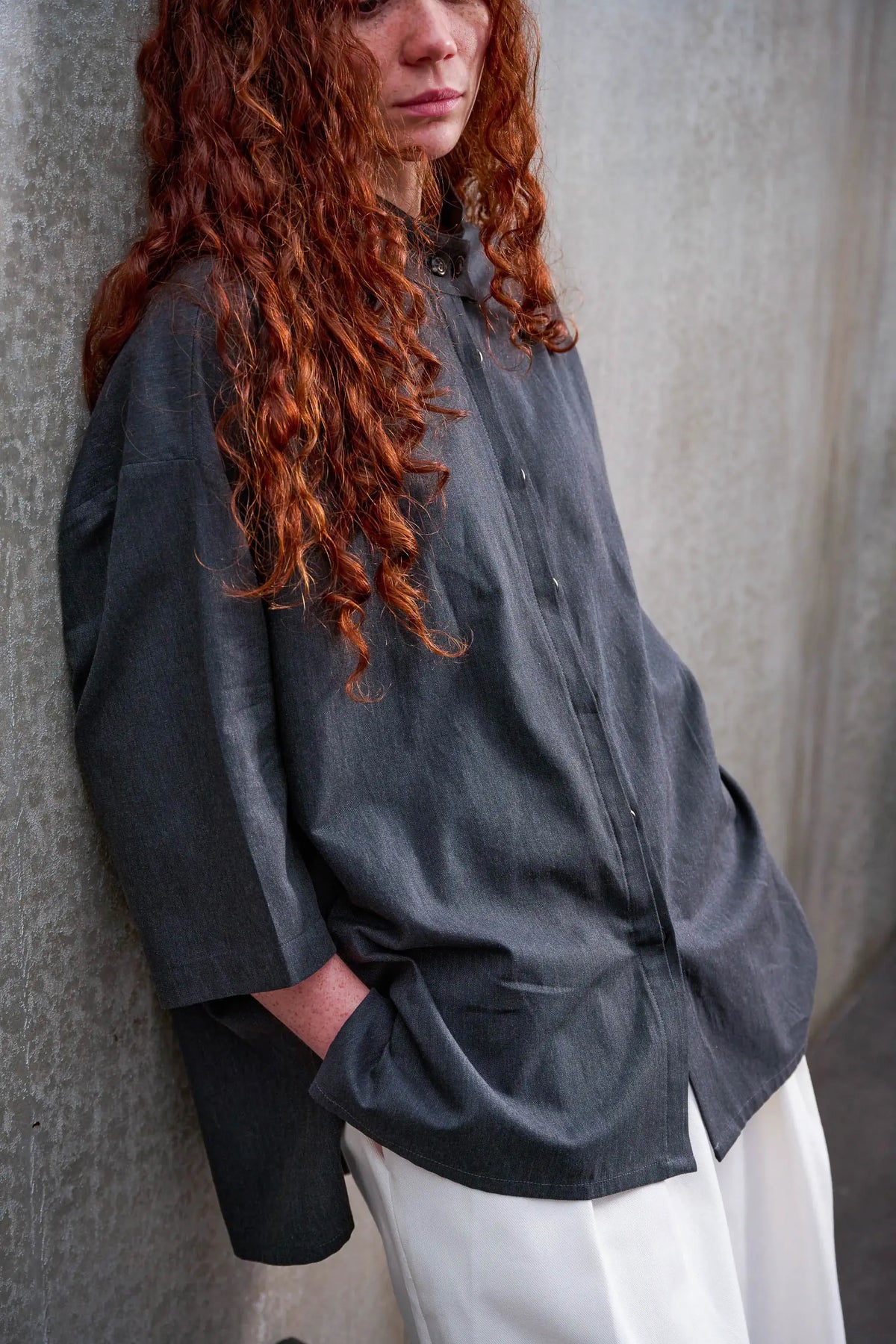 Chemise boxy à col officier de la marque Aïdama, modèle Kita en coton gris foncé. Portée par une mannequin femme et vue de trois quarts centrée sur le buste.