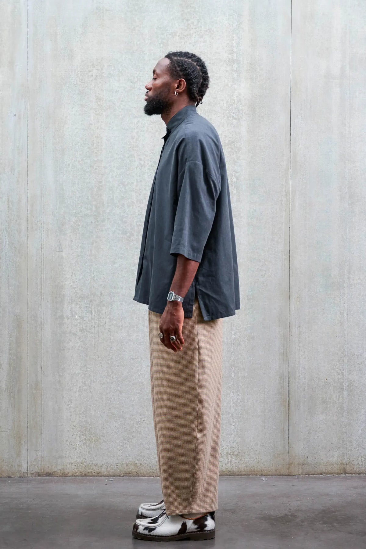 Chemise boxy à col officier de la marque Aïdama, modèle Kita en coton gris foncé. Portée par un mannequin homme et vue de profil.